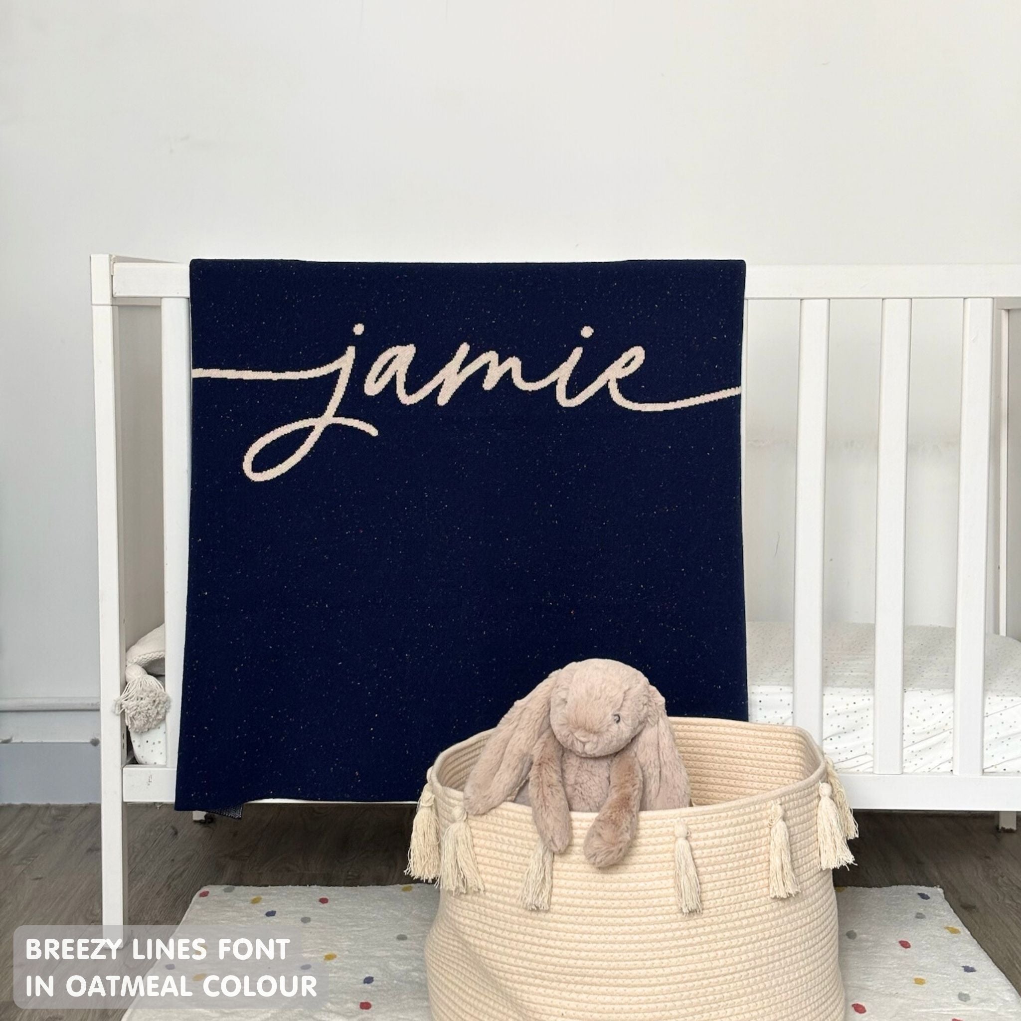Knitted baby blanket in navy and oatmeal with a confetti pattern, customised with baby's name, made by TinyBitz.