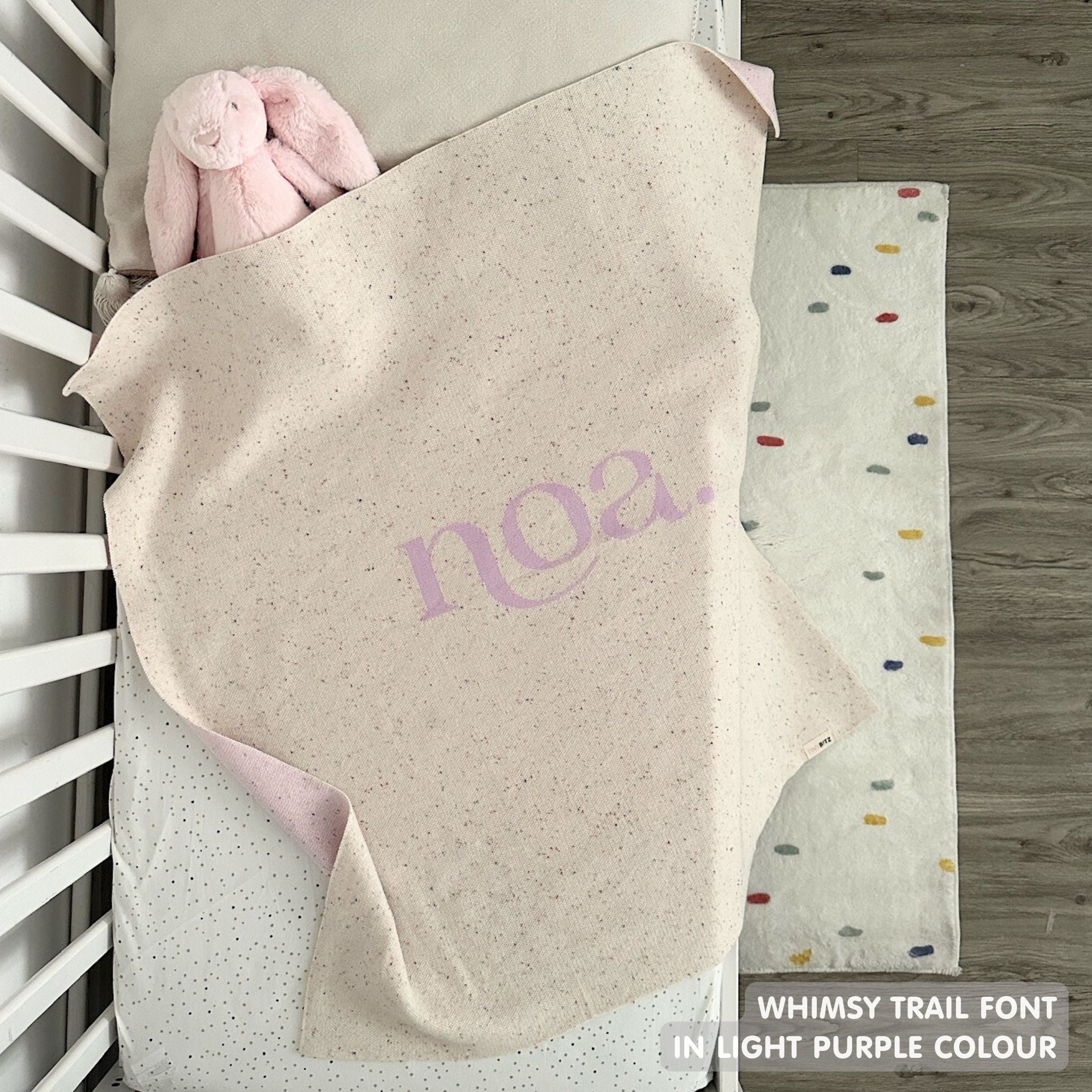 Knitted baby blanket in cream and light purple with a confetti pattern, customised with baby's name, made by TinyBitz.