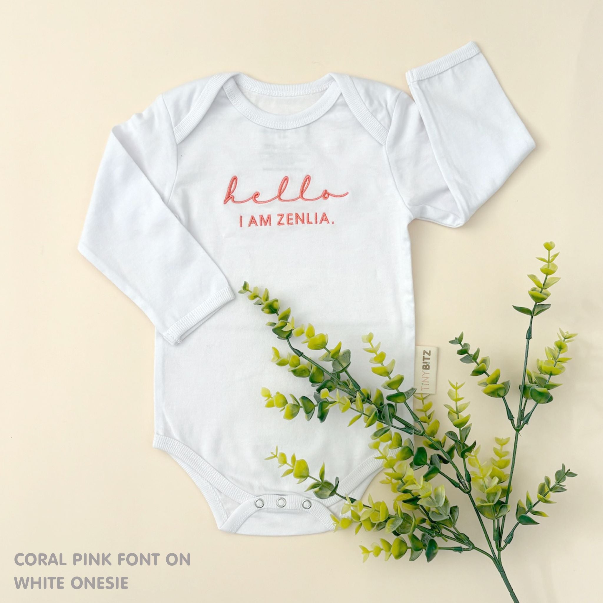 TinyBitz Custom baby onesie in white with name embroidery, unique outfit for baby’s birth announcement or first photoshoot.