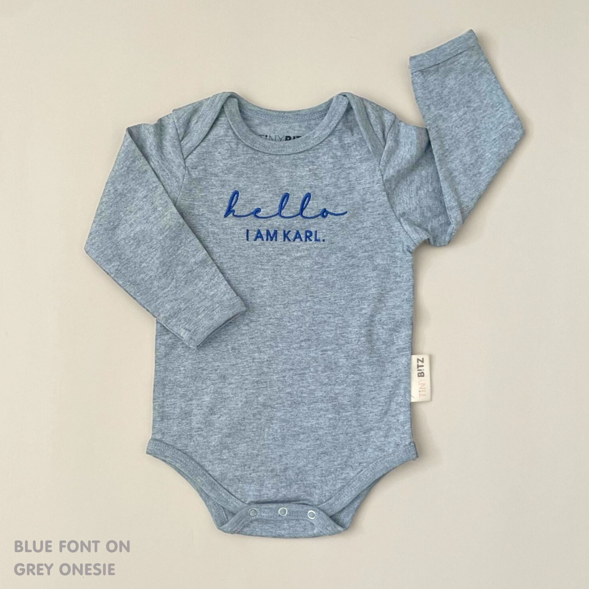Neutral-tone personalised baby onesie featuring custom name, made-to-order newborn gift by TinyBitz.