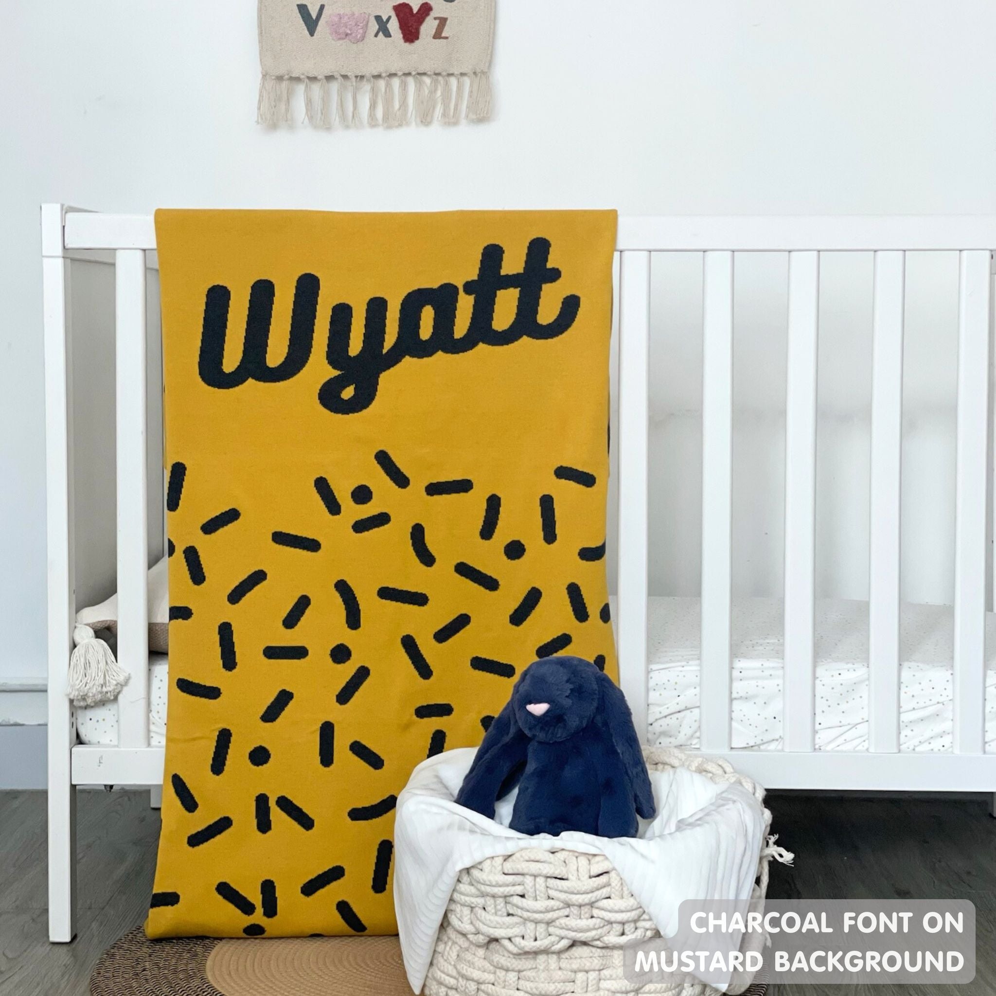 TinyBitz knitted name blanket in mustard and charcoal with a confetti pattern, a lovely touch to decorate your baby's room!