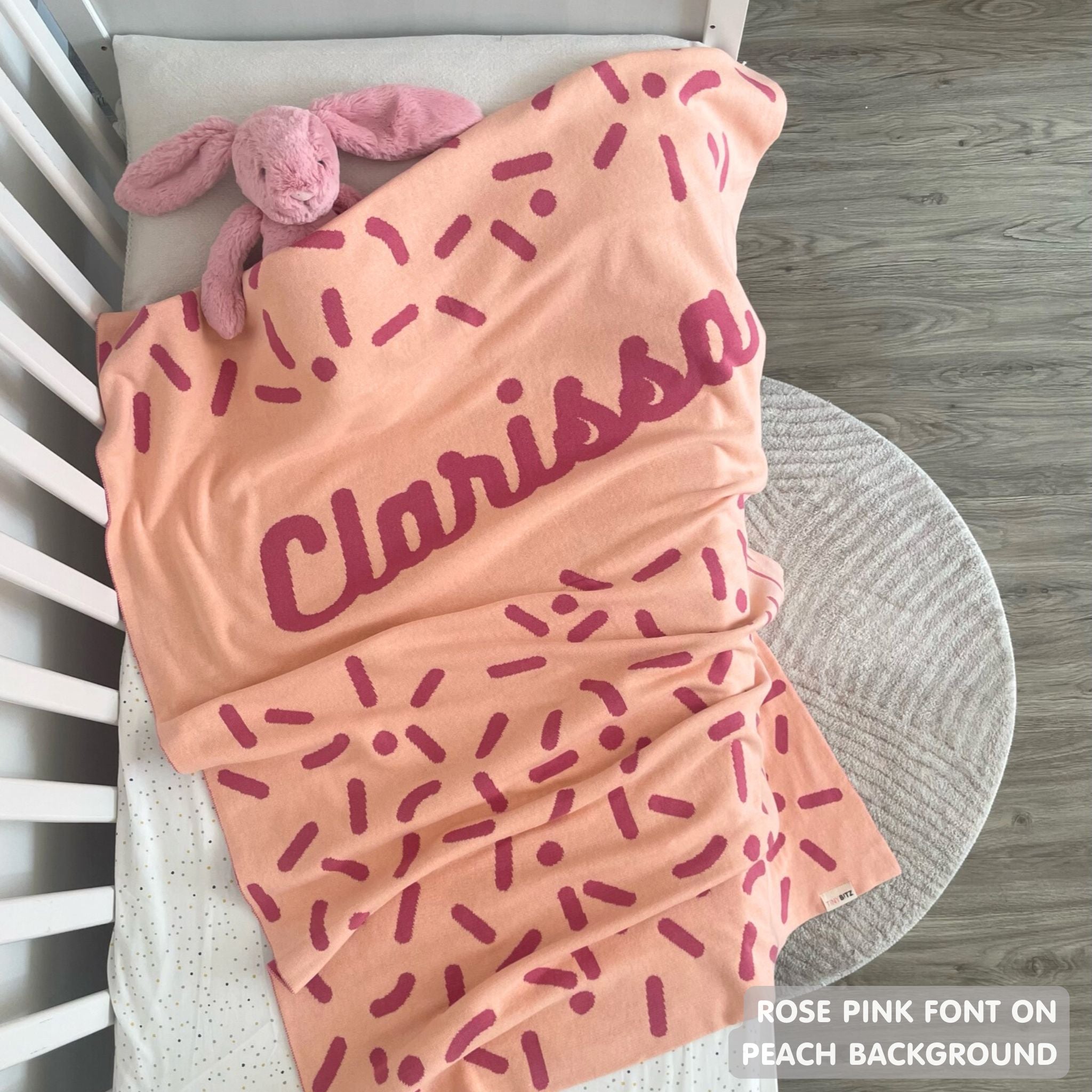 TinyBitz knitted name blanket in peach and rose pink with a confetti pattern, a lovely touch to decorate your baby's room!