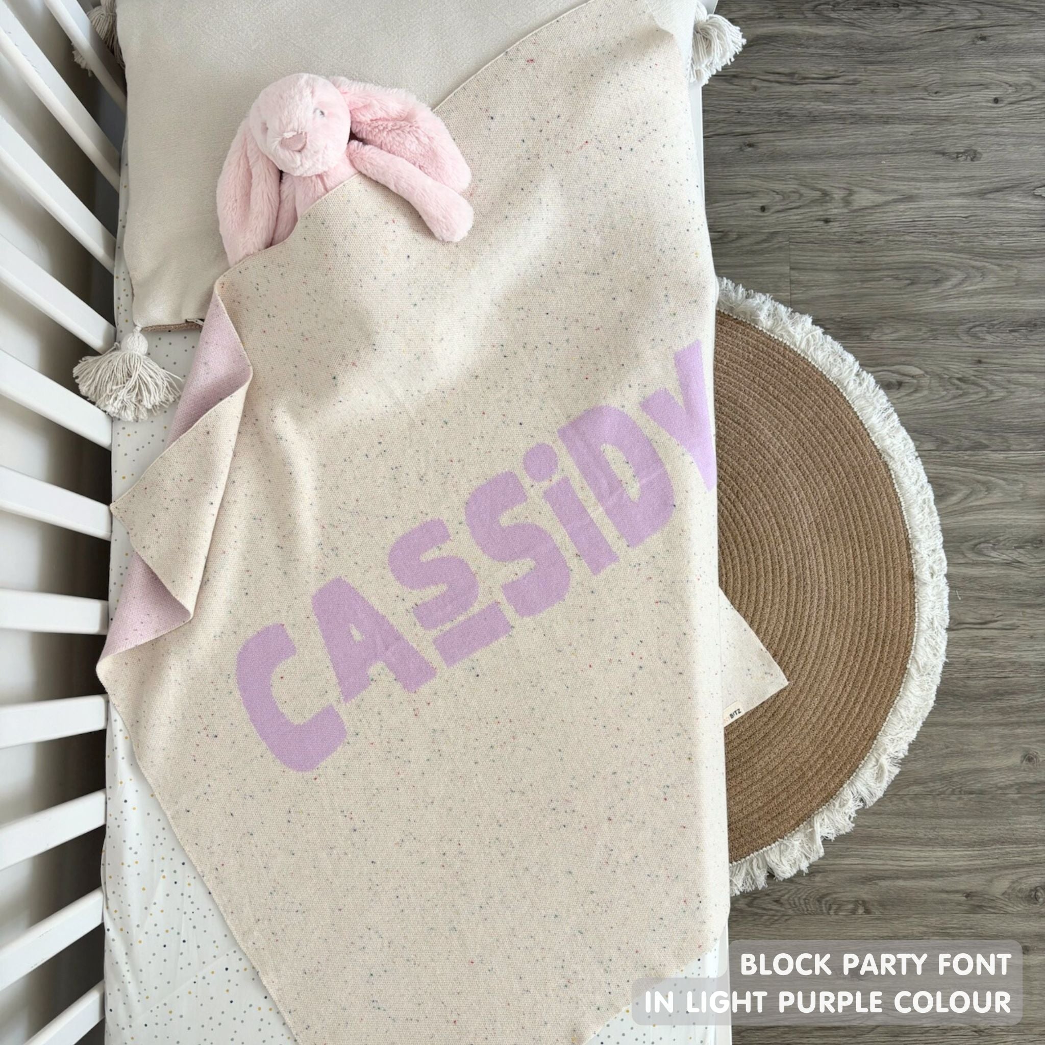 TinyBitz knitted name blanket in cream and light purple with a confetti pattern, a lovely touch to decorate your baby's room!