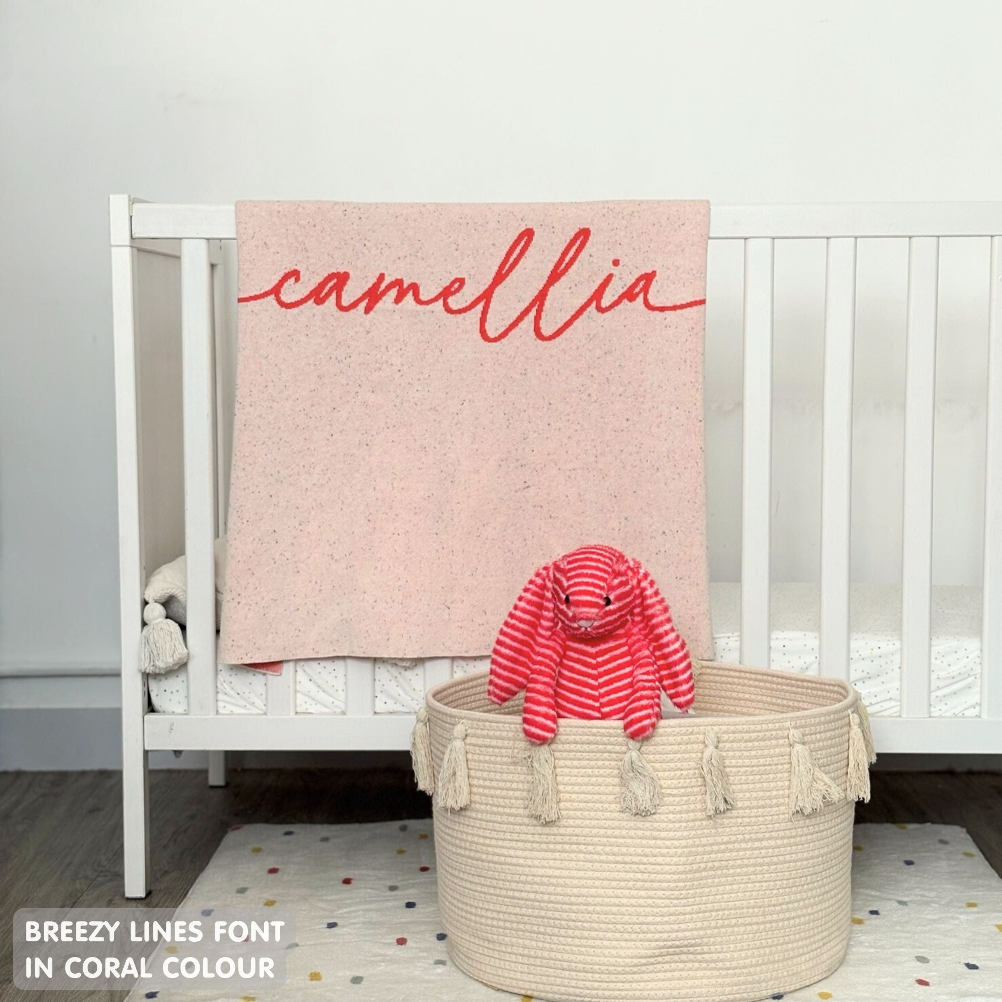 Cotton baby blanket with baby's name knitted in cream and coral with a confetti pattern, made by TinyBitz.