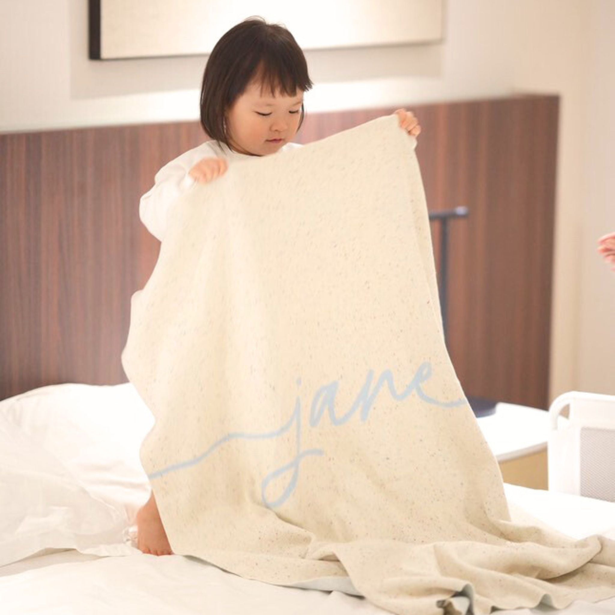 Knitted baby blanket in cream and light blue with a confetti pattern, customised with baby's name, made by TinyBitz.