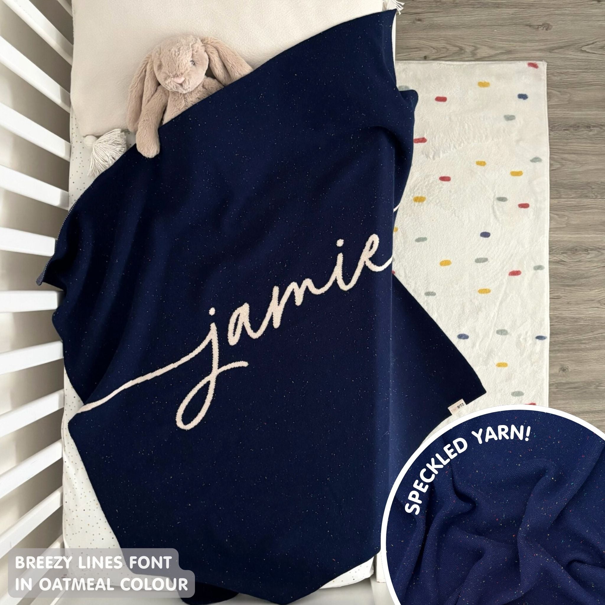 Knitted baby blanket in navy and oatmeal with a confetti pattern, customised with baby's name, made by TinyBitz.