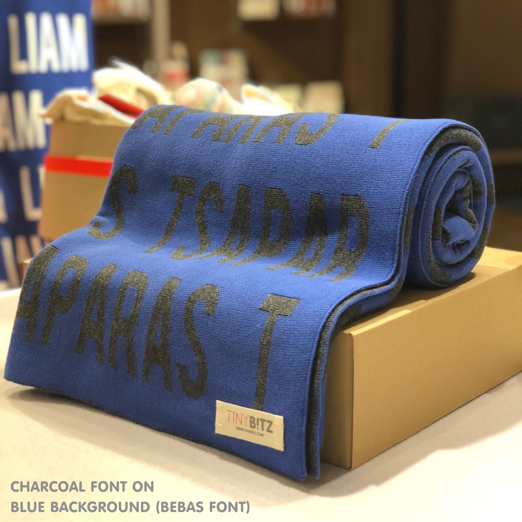 Knitted baby blanket in blue and charcoal, customised with baby's name, made by TinyBitz.