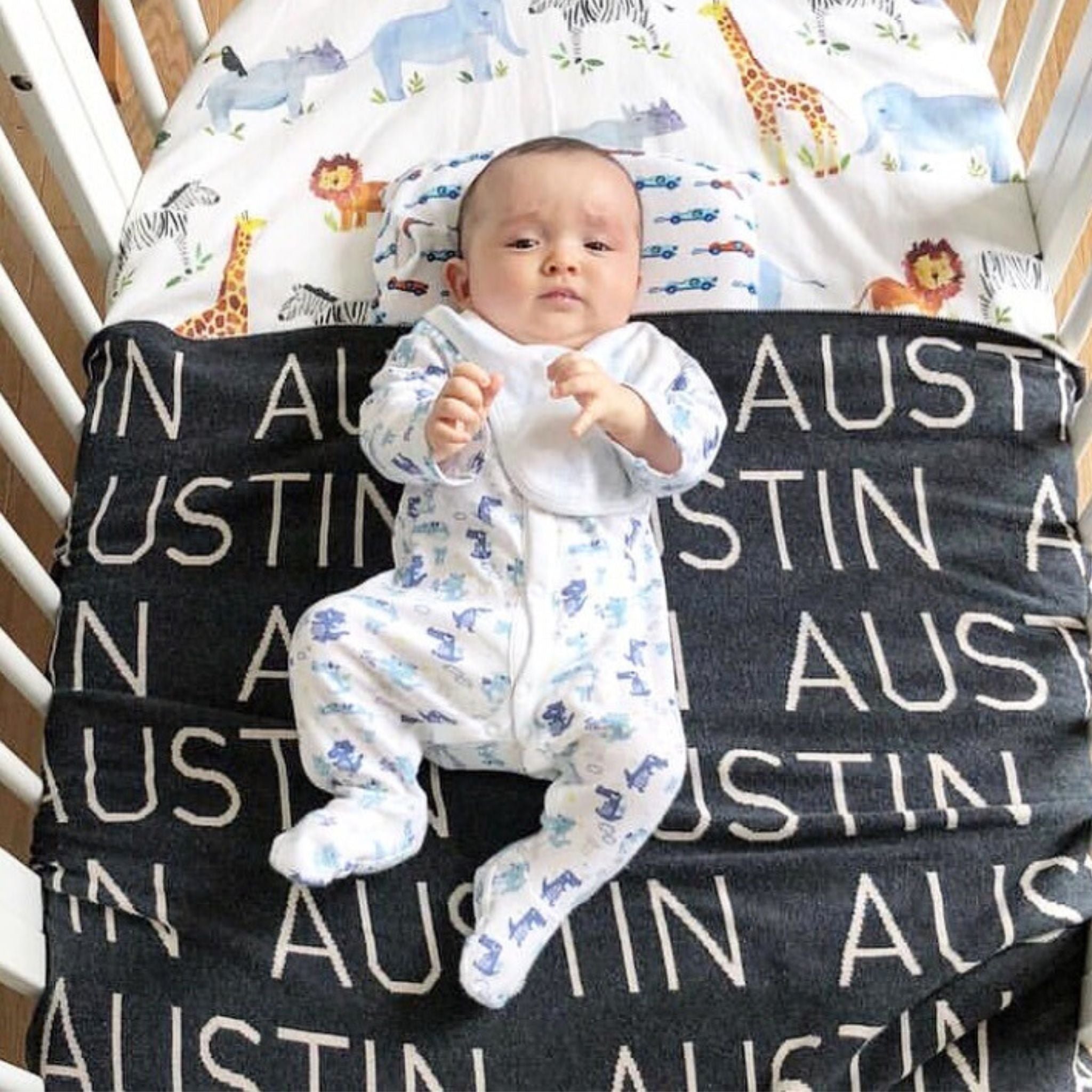 TinyBitz personalized knitted blanket in charcoal background, customized with baby's name and made from 100% cotton.