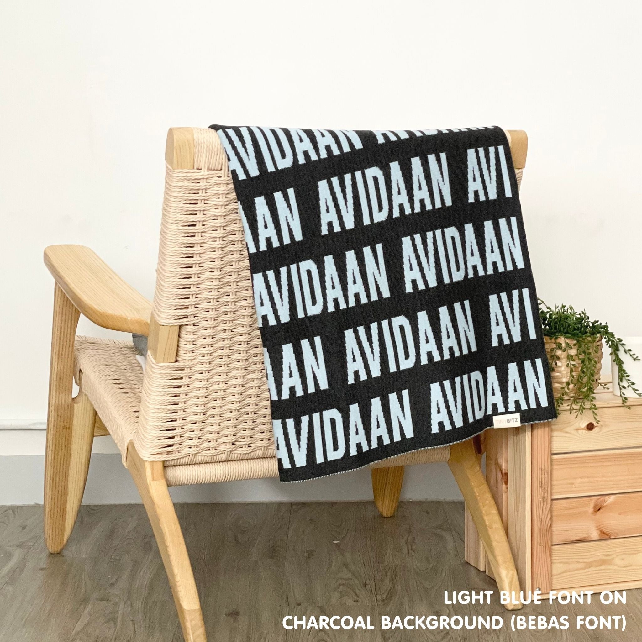 Customisable blanket with adult's name knitted in charcoal and light blue, personalized by TinyBitz.