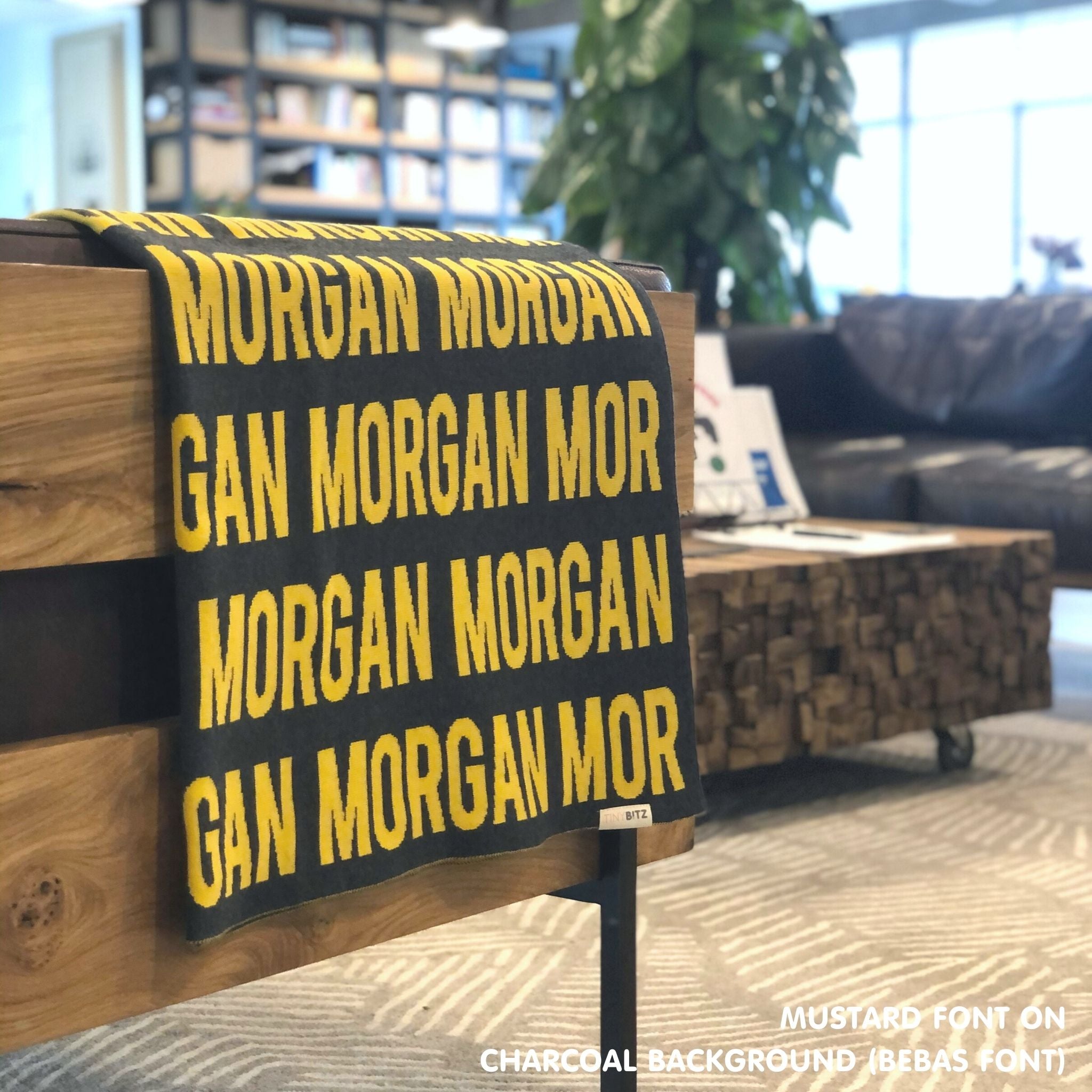 Custom name blanket in charcoal and mustard draped over a chair makes the best personalized home decor.
