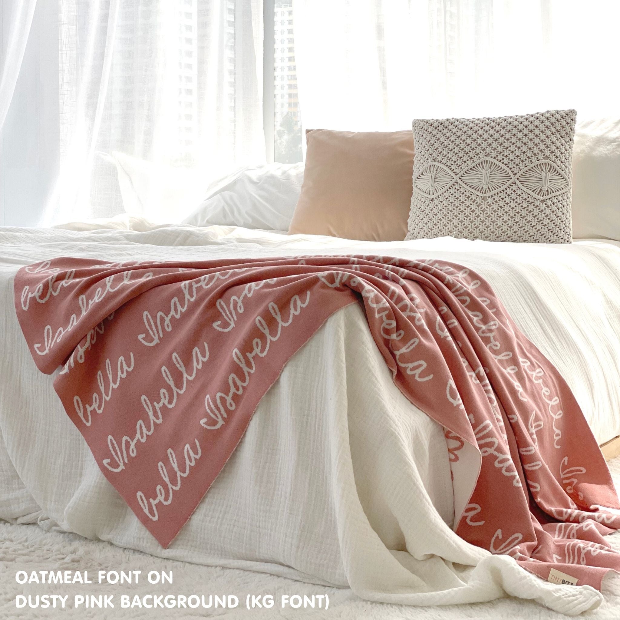 Custom name blanket draped on bed, knitted in dusty pink and oatmeal makes the best personalised home decor.