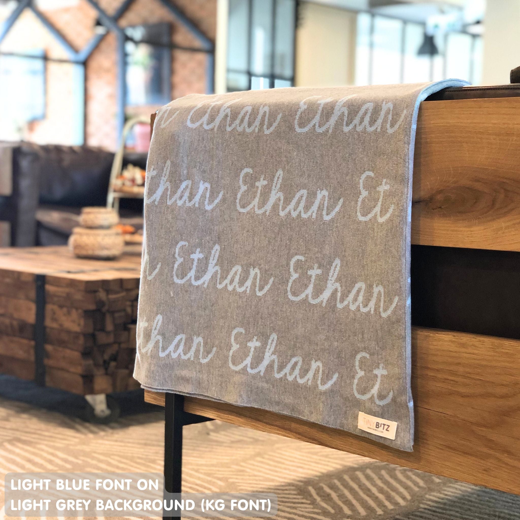Custom name blanket in light grey and light blue draped over a chair makes the best personalized home decor.