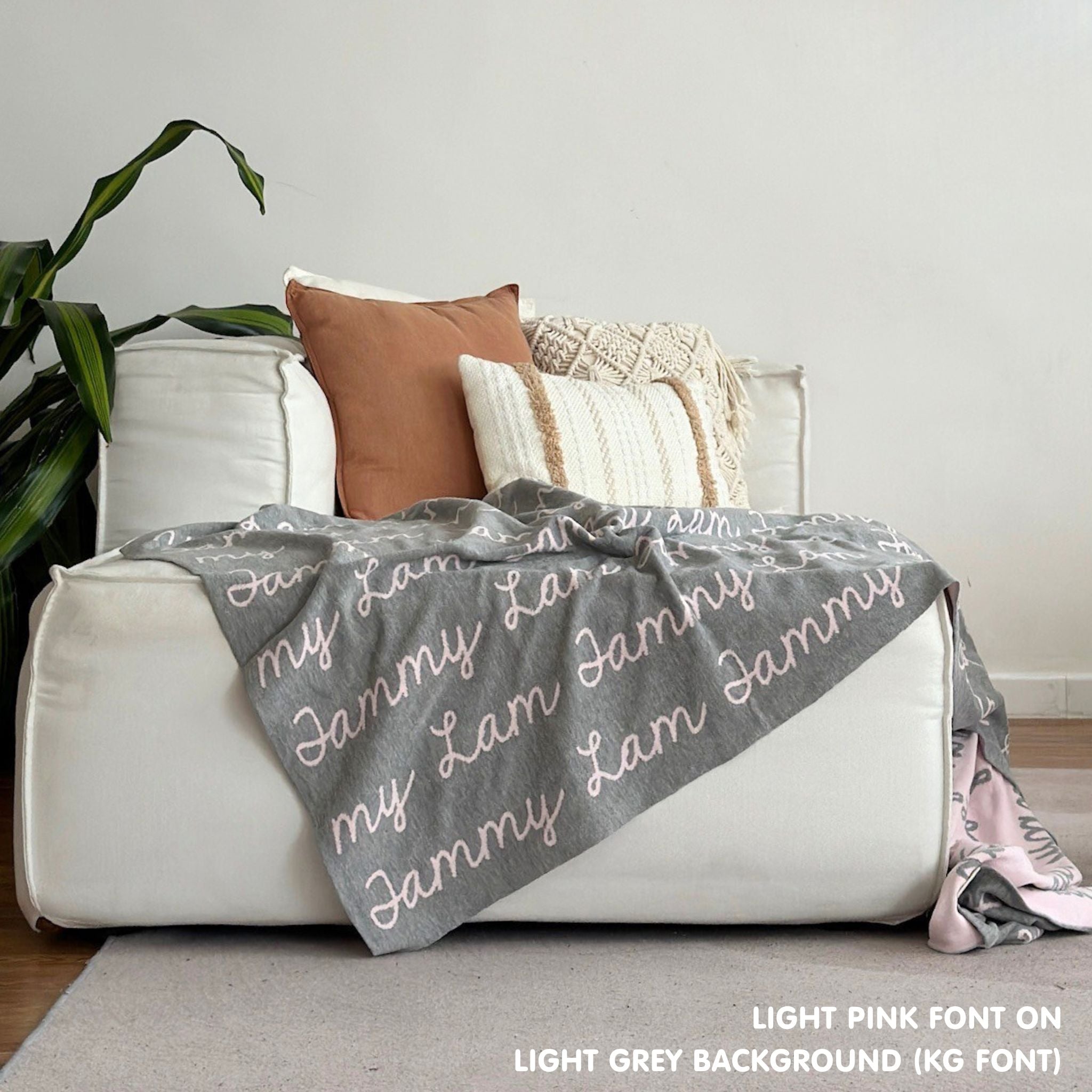 Custom name blanket draped on sofa, knitted in light grey and light pink makes the best personalised home decor.
