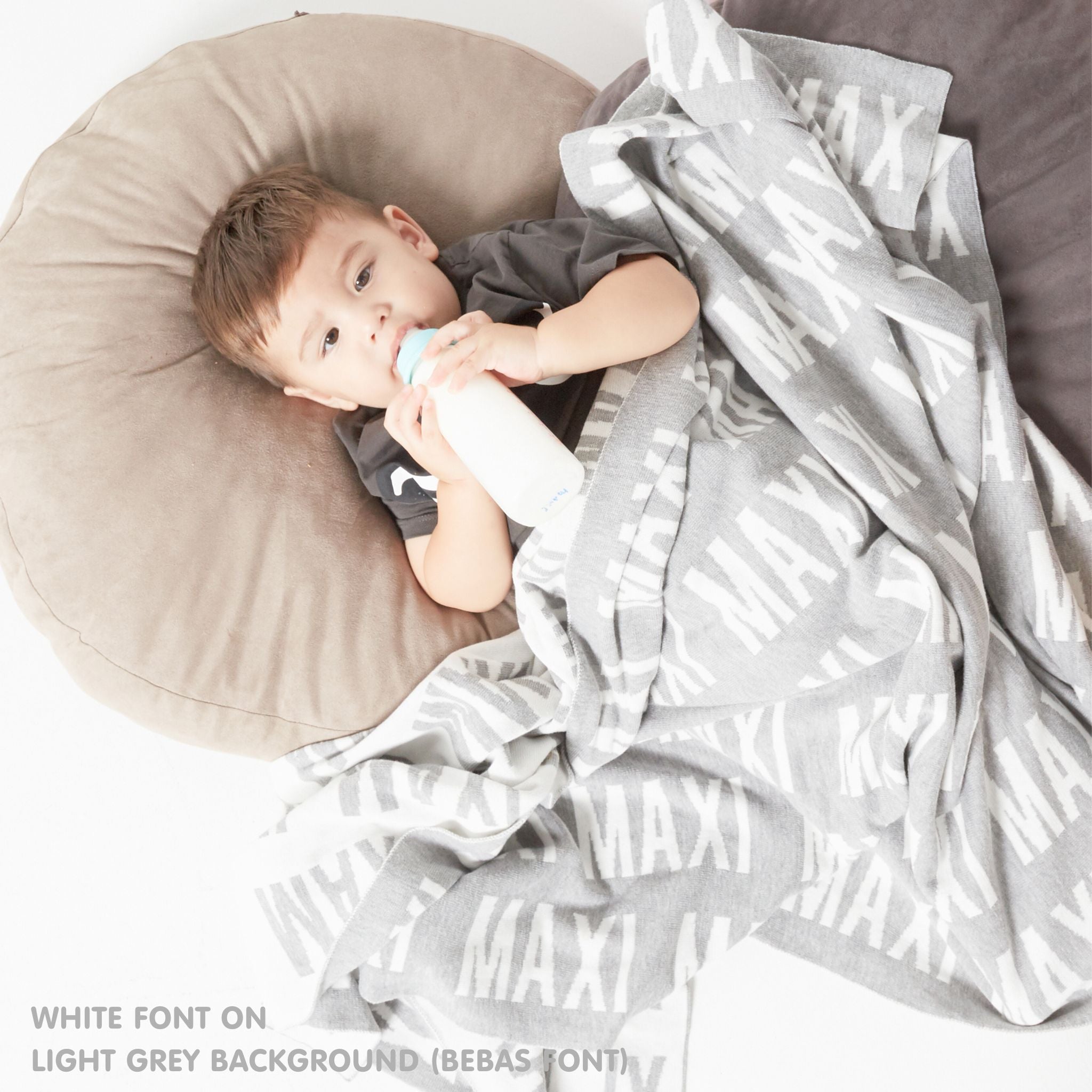 TinyBitz personalized knitted blanket in light grey background, customized with baby's name and made from 100% cotton.