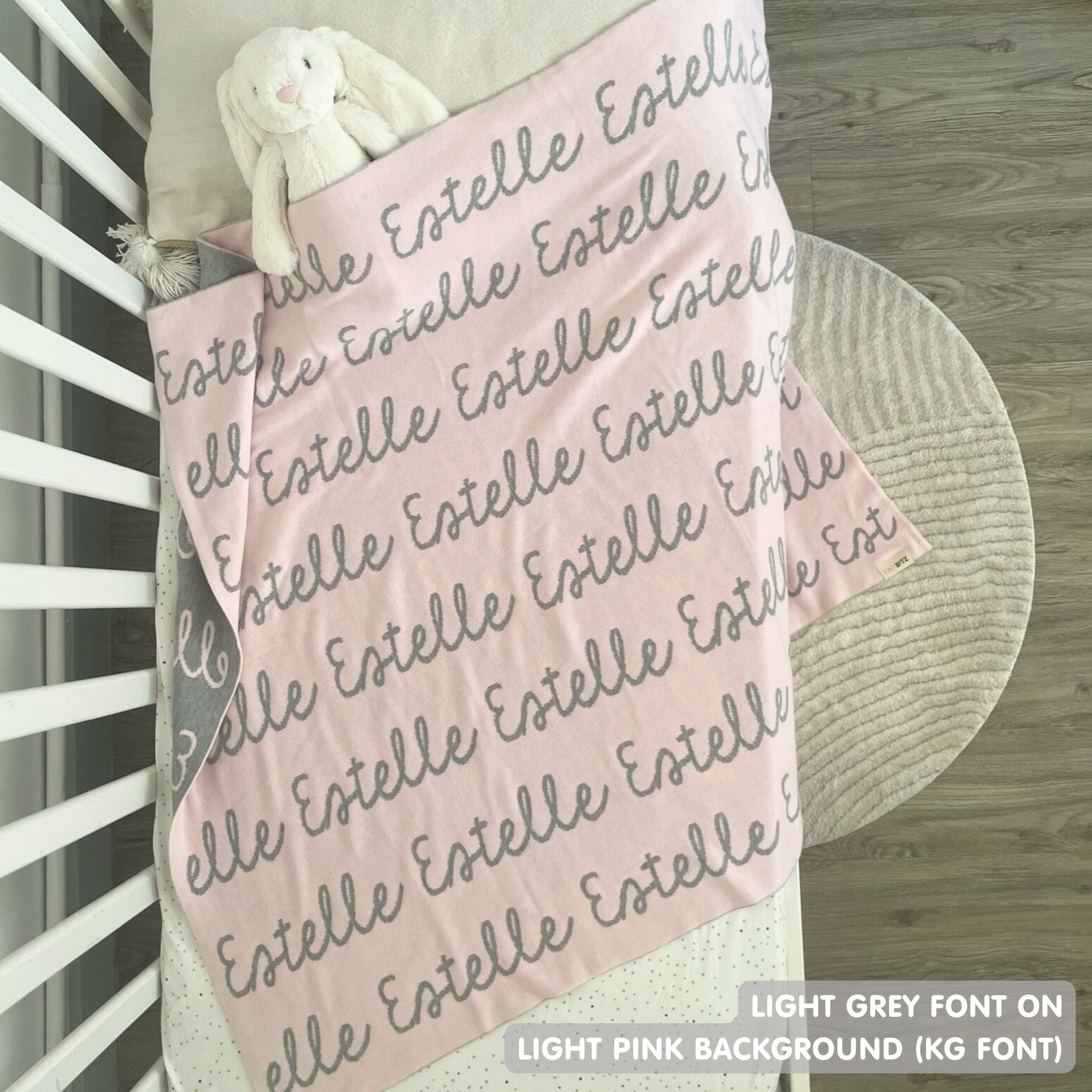 TinyBitz knitted baby girls blanket in light pink background and light grey, personalized with your baby’s name.