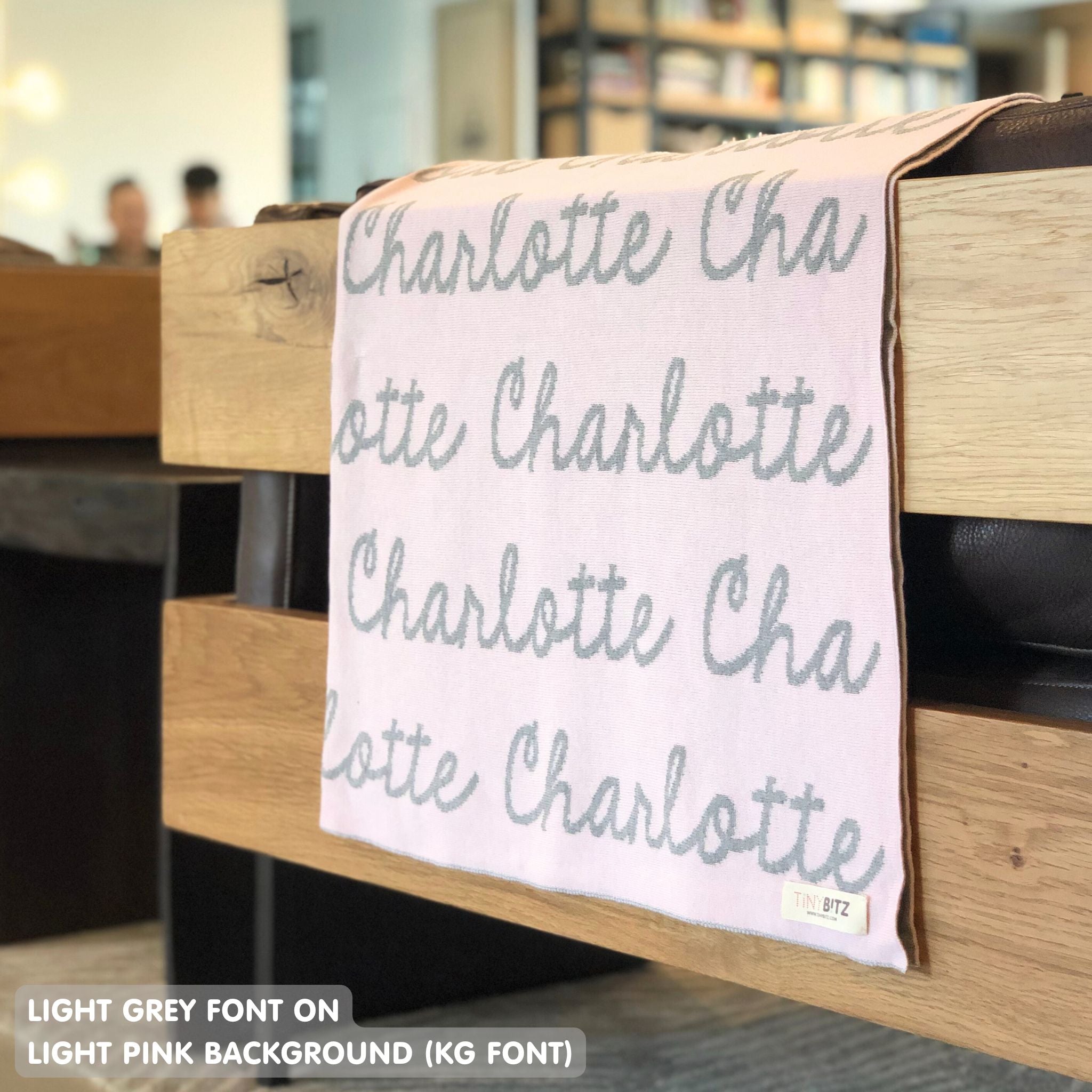 Custom name blanket in light pink and light grey draped over a chair makes the best personalized home decor.