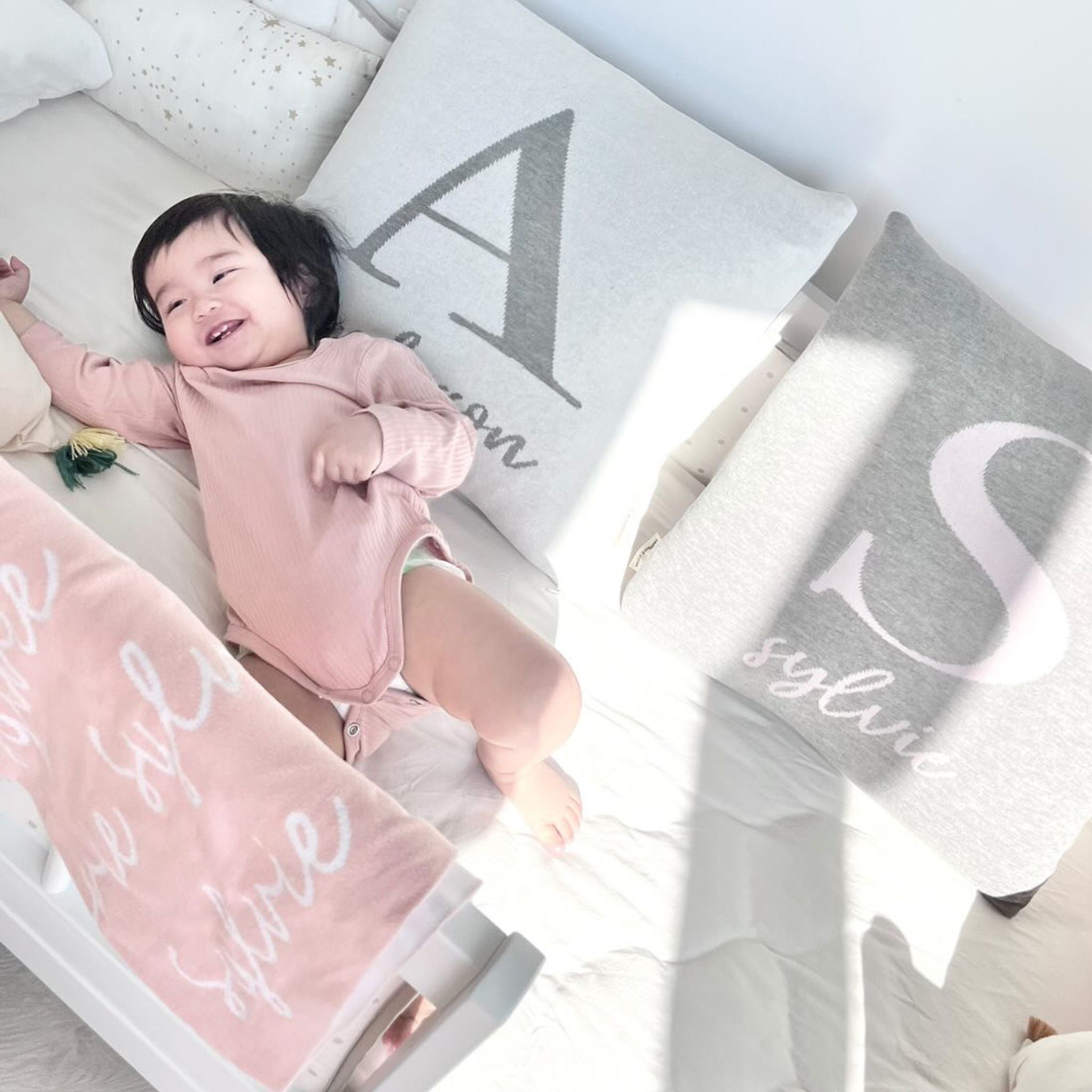 Knitted baby blanket in light pink background, customised with baby's name, made by TinyBitz.