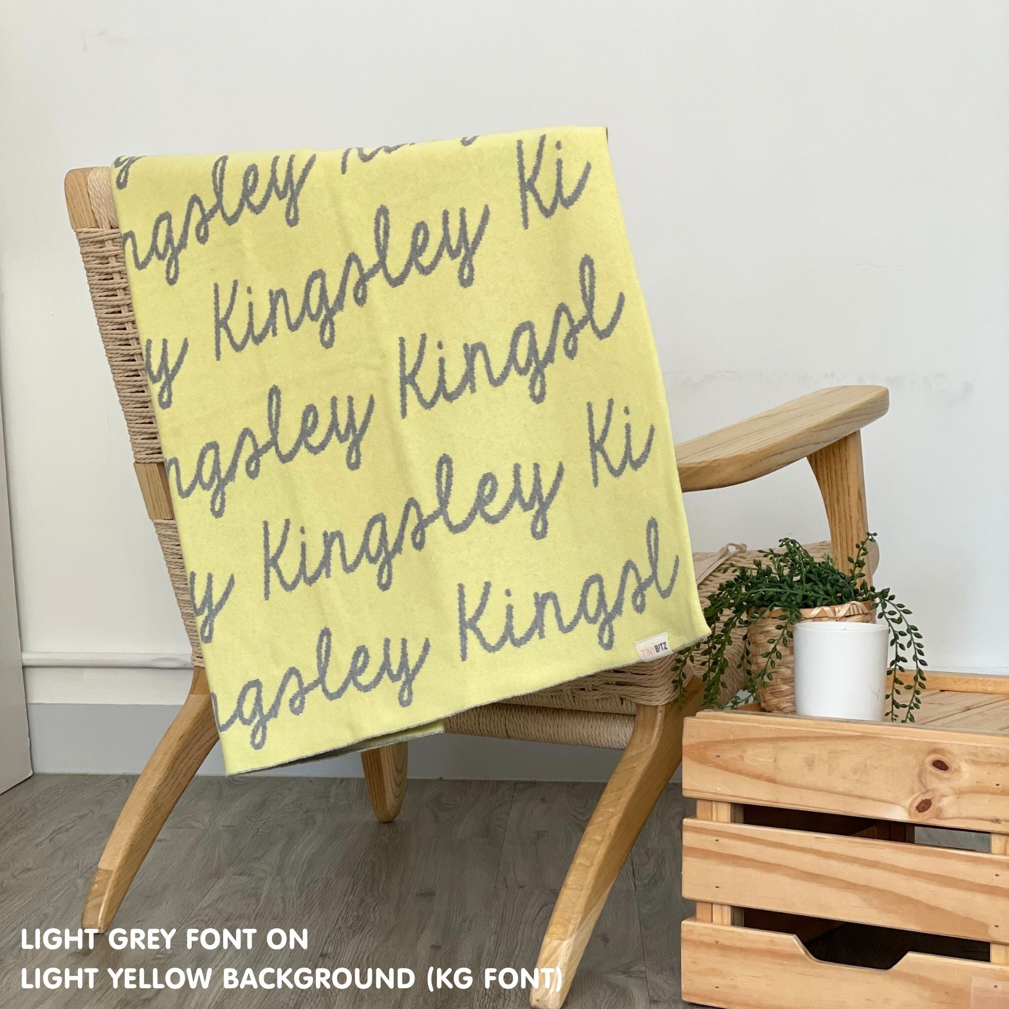 Custom name blanket in light yellow and light grey draped over a chair makes the best personalized home decor.
