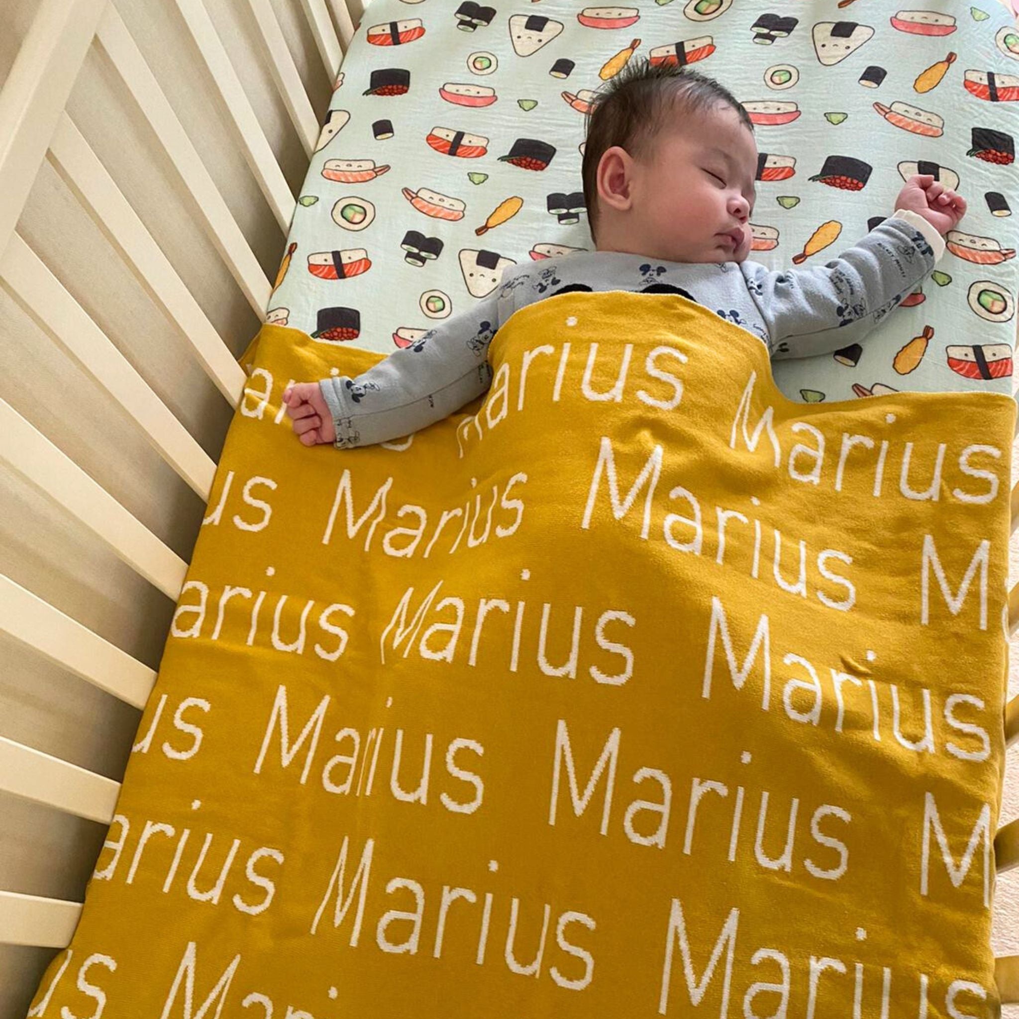 TinyBitz personalized knitted blanket in mustard background, customized with baby's name and made from 100% cotton.