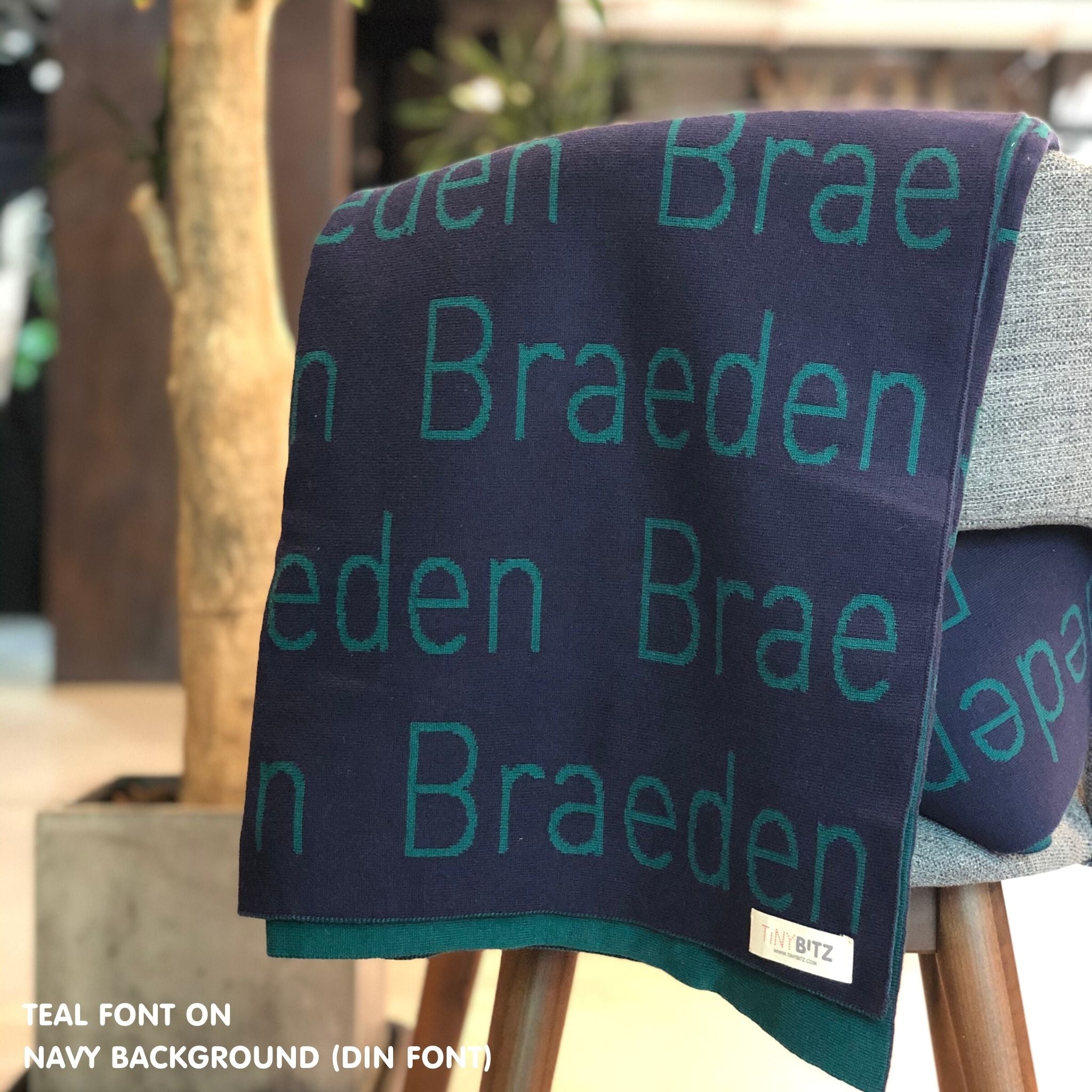 Custom name blanket in navy and teal draped over a chair makes the best personalized home decor.