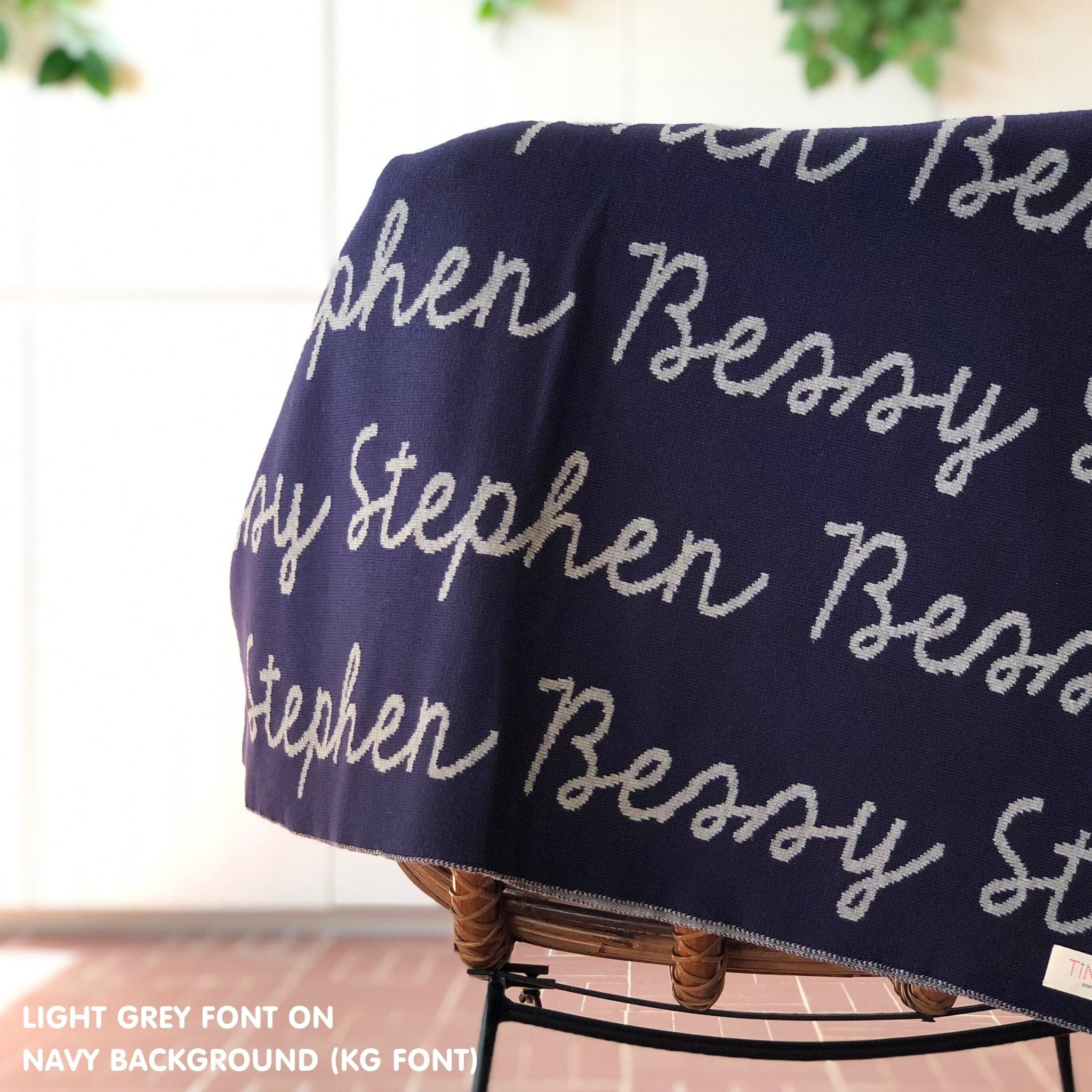 Custom name blanket in navy and light grey draped over a chair makes the best personalized home decor.