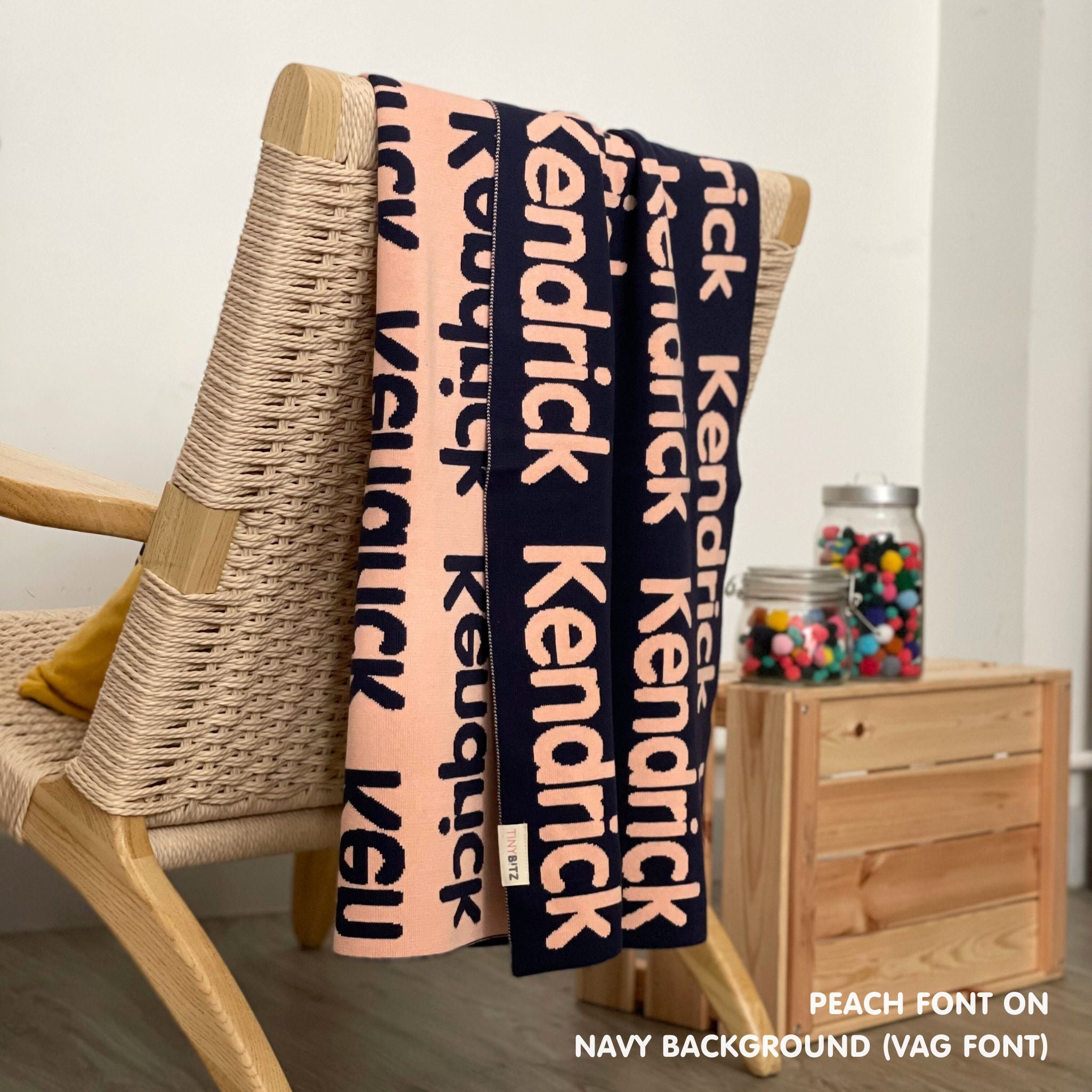 Personalised pet blanket in navy and peach knitted cotton, custom dog blanket by TinyBitz, styled on modern wooden dog bed.