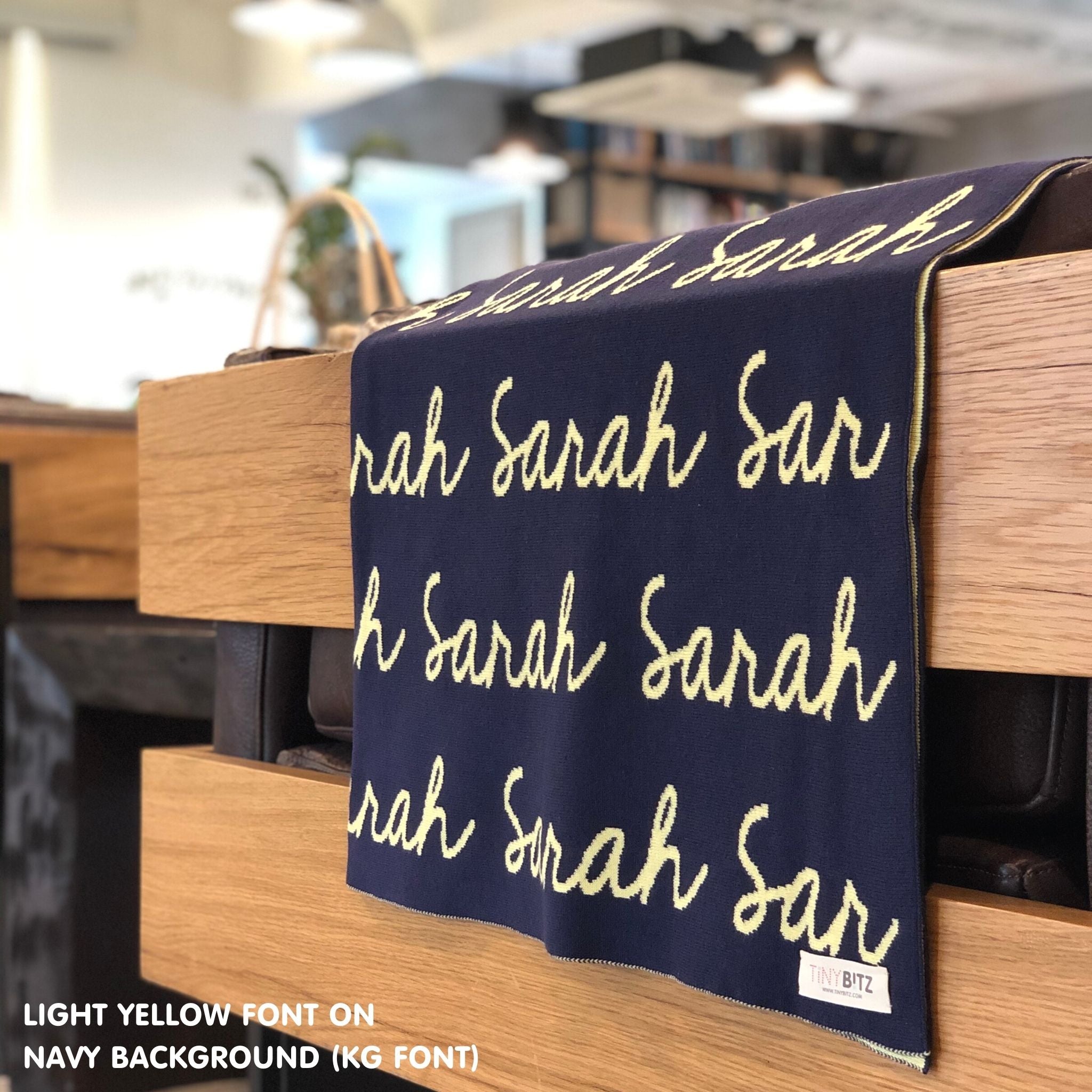 Custom name blanket in navy and light yellow draped over a chair makes the best personalized home decor.