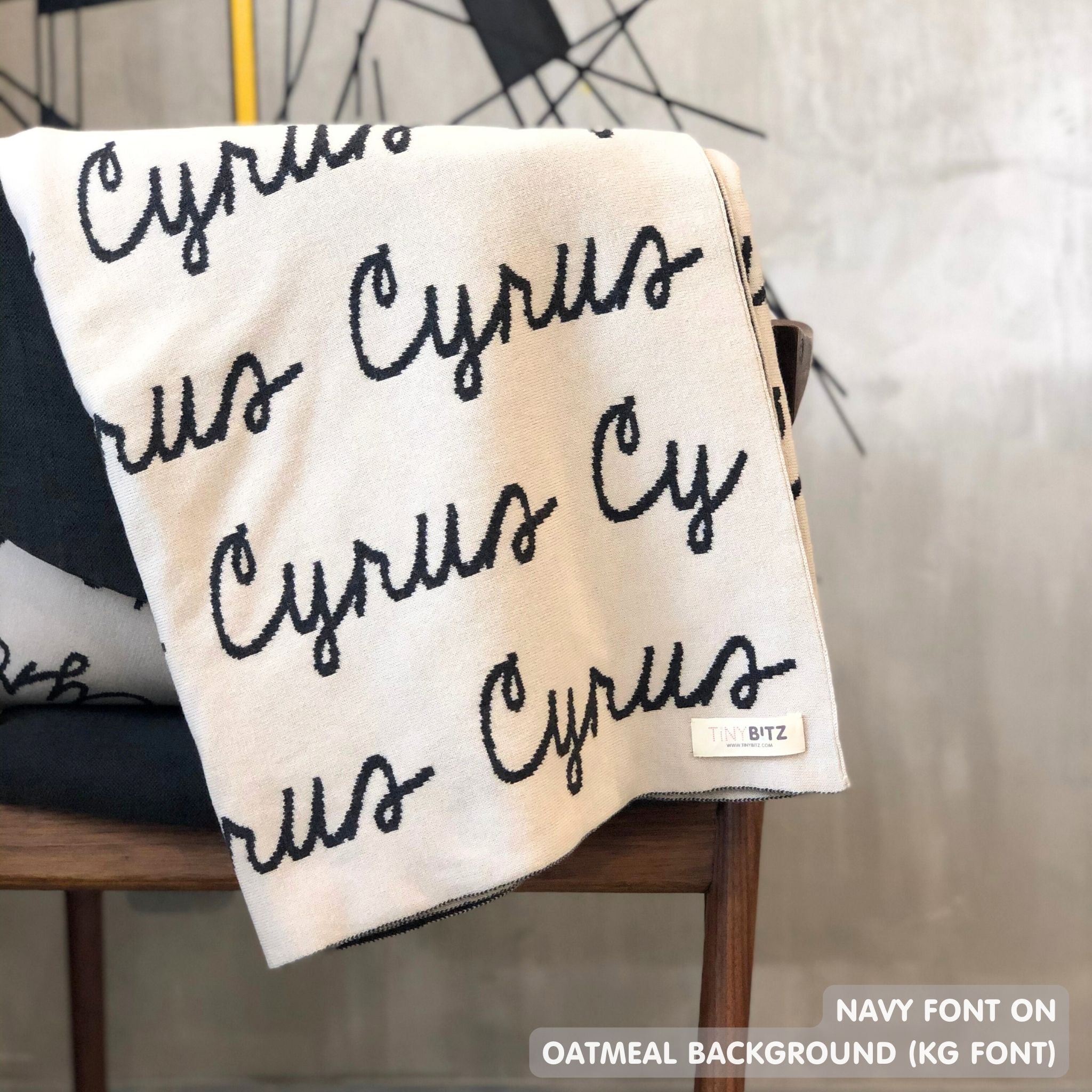 Custom name blanket in oatmeal and navy draped over a chair makes the best personalized home decor.