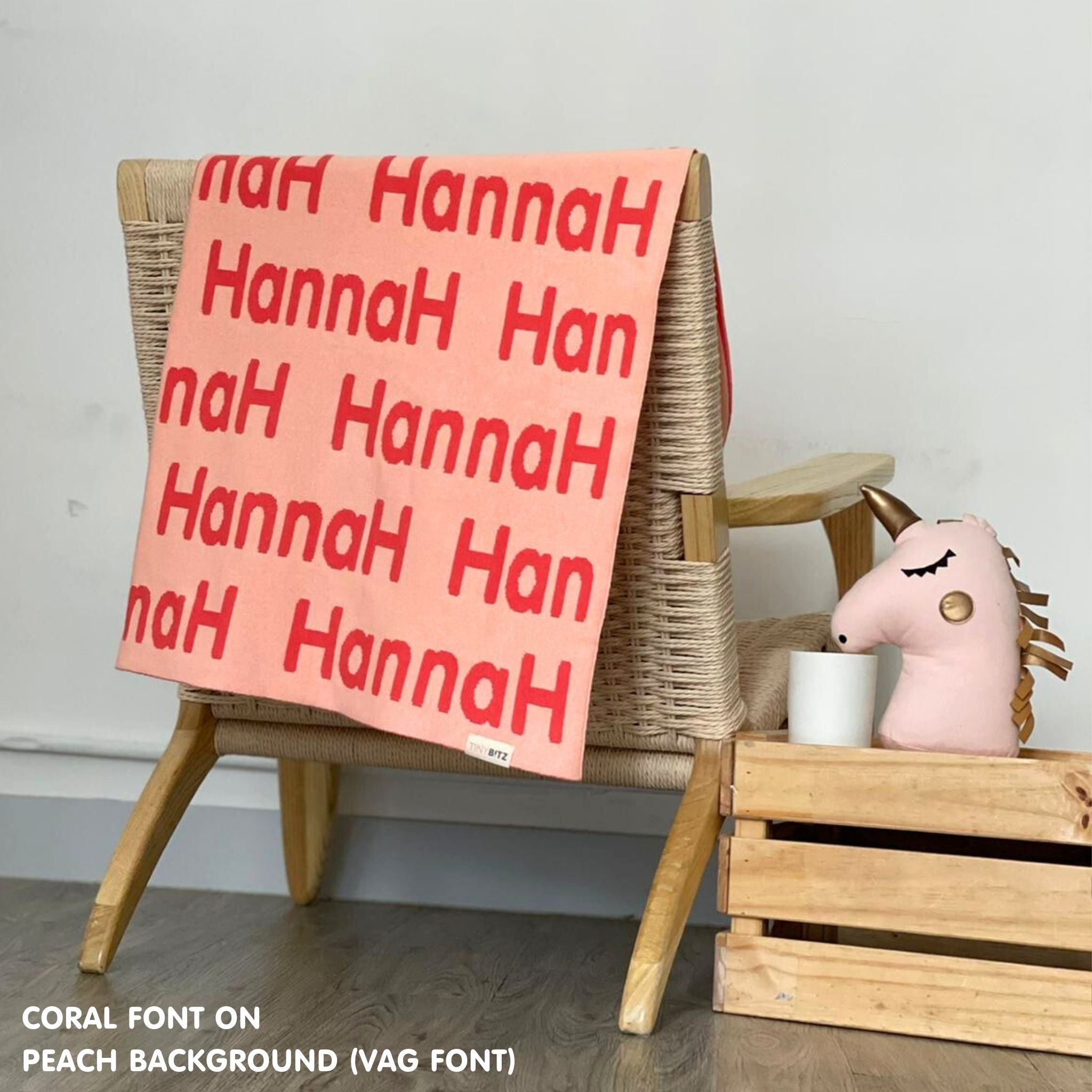 Customisable blanket with adult's name knitted in peach and coral, personalized by TinyBitz.