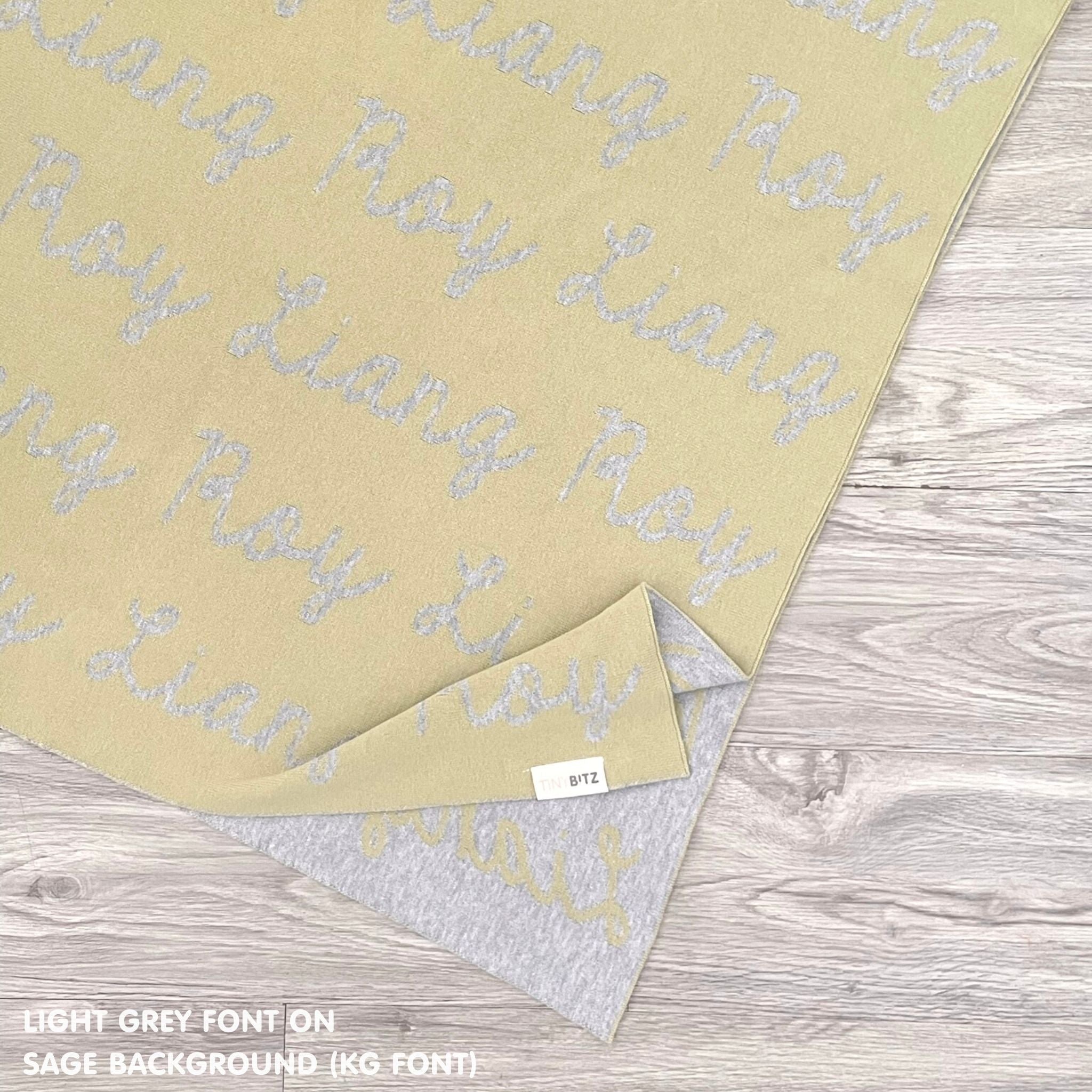 Personalized blanket with couple's name knitted in sage and light grey, made by TinyBitz.