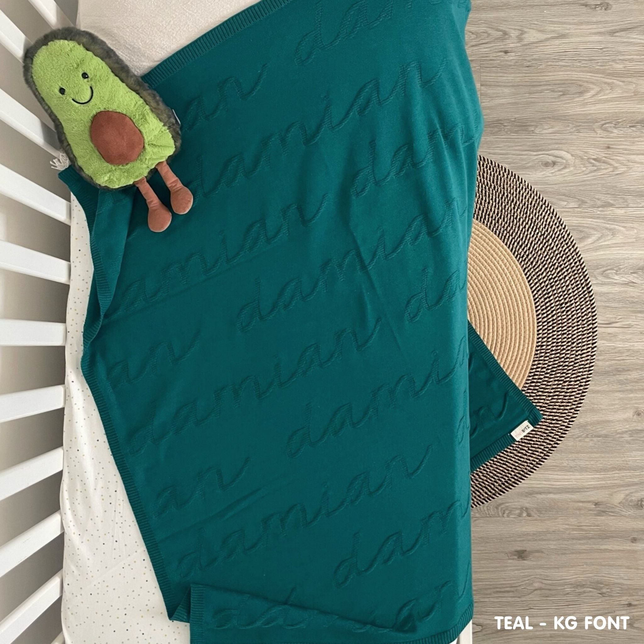 TinyBitz knitted name blanket in teal background, one colour with monogram, can be used to decorate your baby's room!