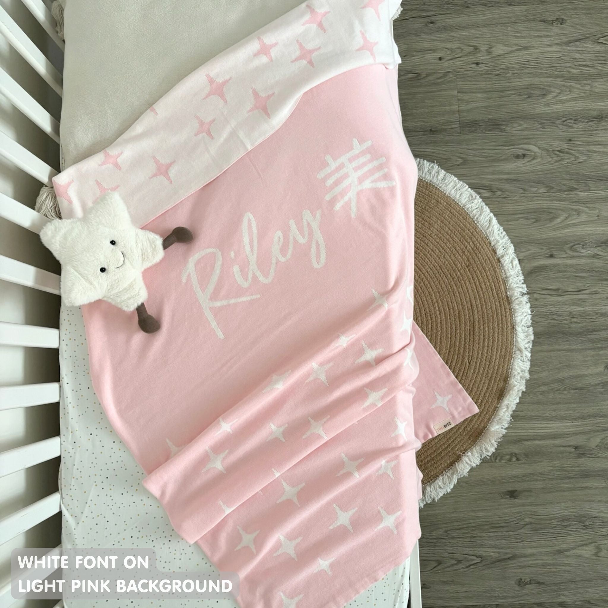 Knitted baby blanket in light pink and white with a twinkles pattern, customised with baby's name, made by TinyBitz.