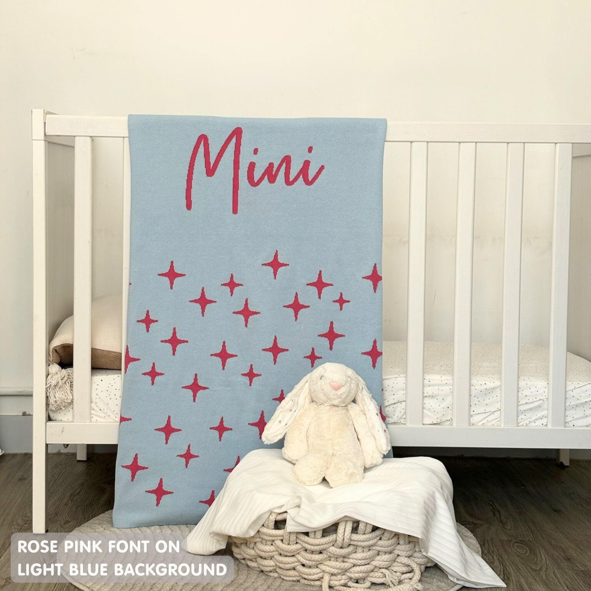 Knitted baby blanket in light blue and rose pink with a twinkles pattern, customised with baby's name, made by TinyBitz.