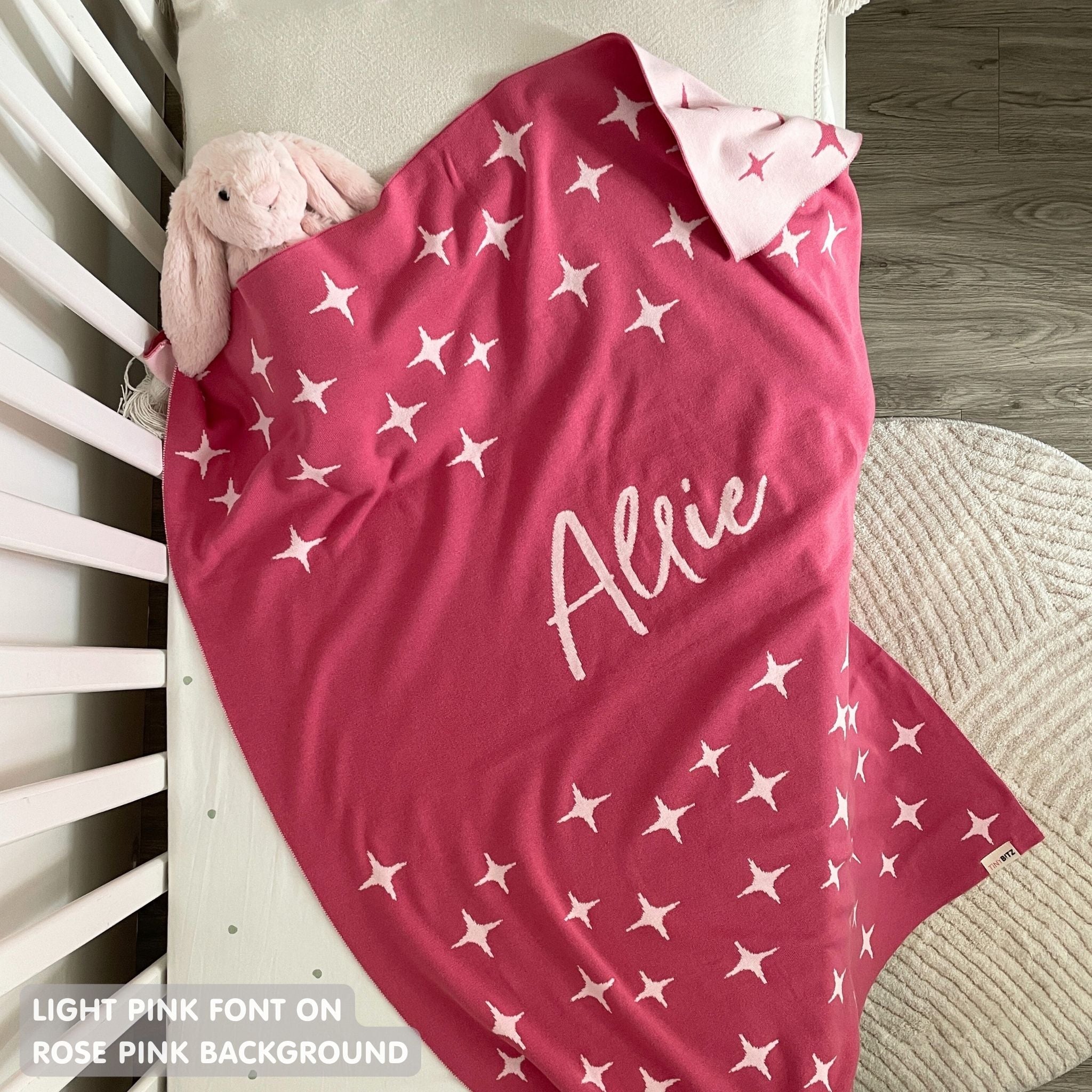 Cotton baby blanket with baby's name knitted in rose pink and light pink with a twinkles pattern, made by TinyBitz.