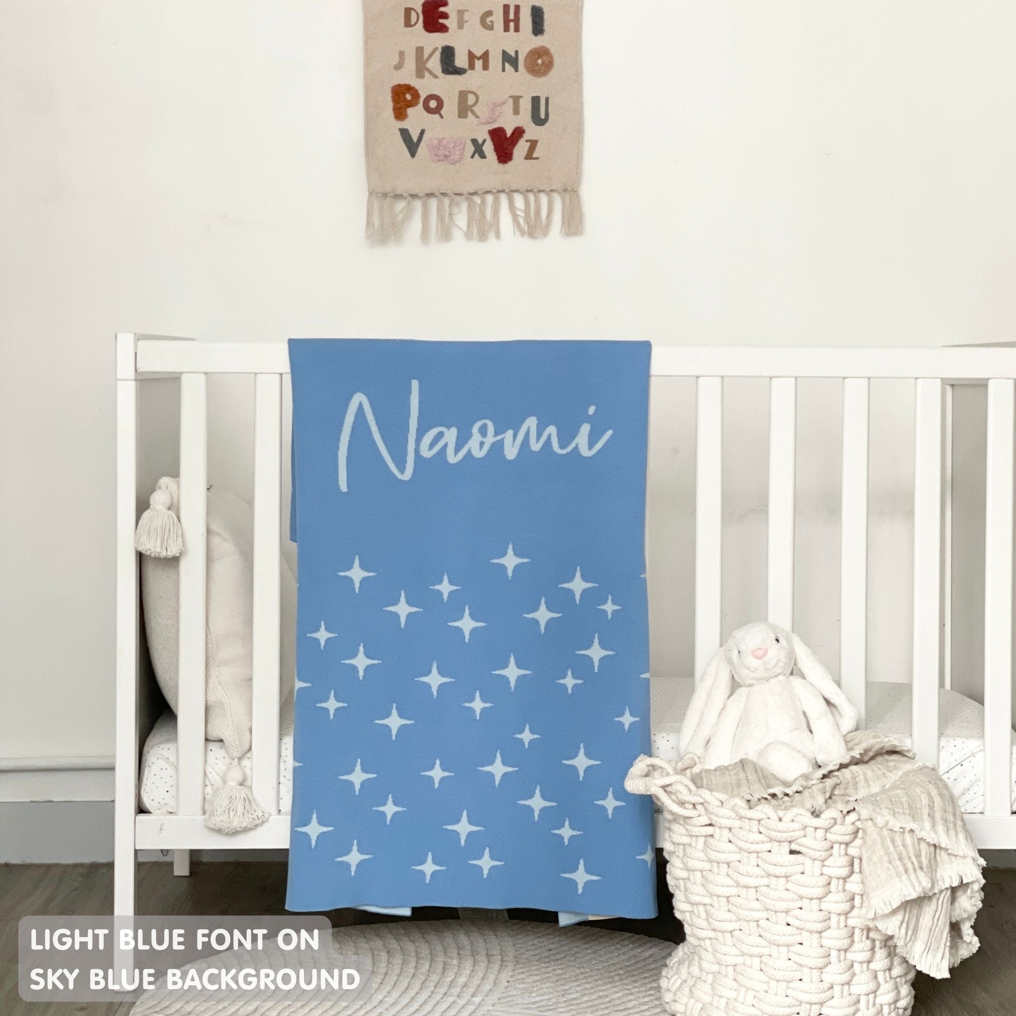 Baby blanket knitted from cotton personalized with baby's name in sky blue and light blue with a twinkles pattern, made by TinyBitz.