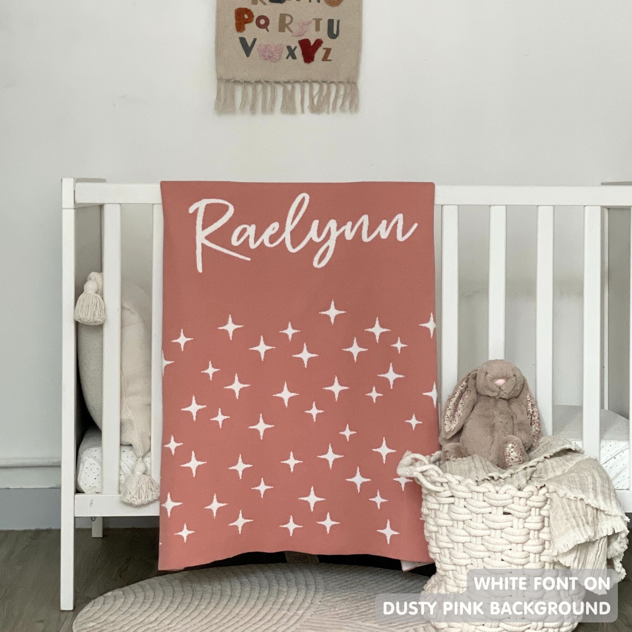 Baby blanket knitted from cotton personalized with baby's name in dusty pink and white with a twinkles pattern, made by TinyBitz.