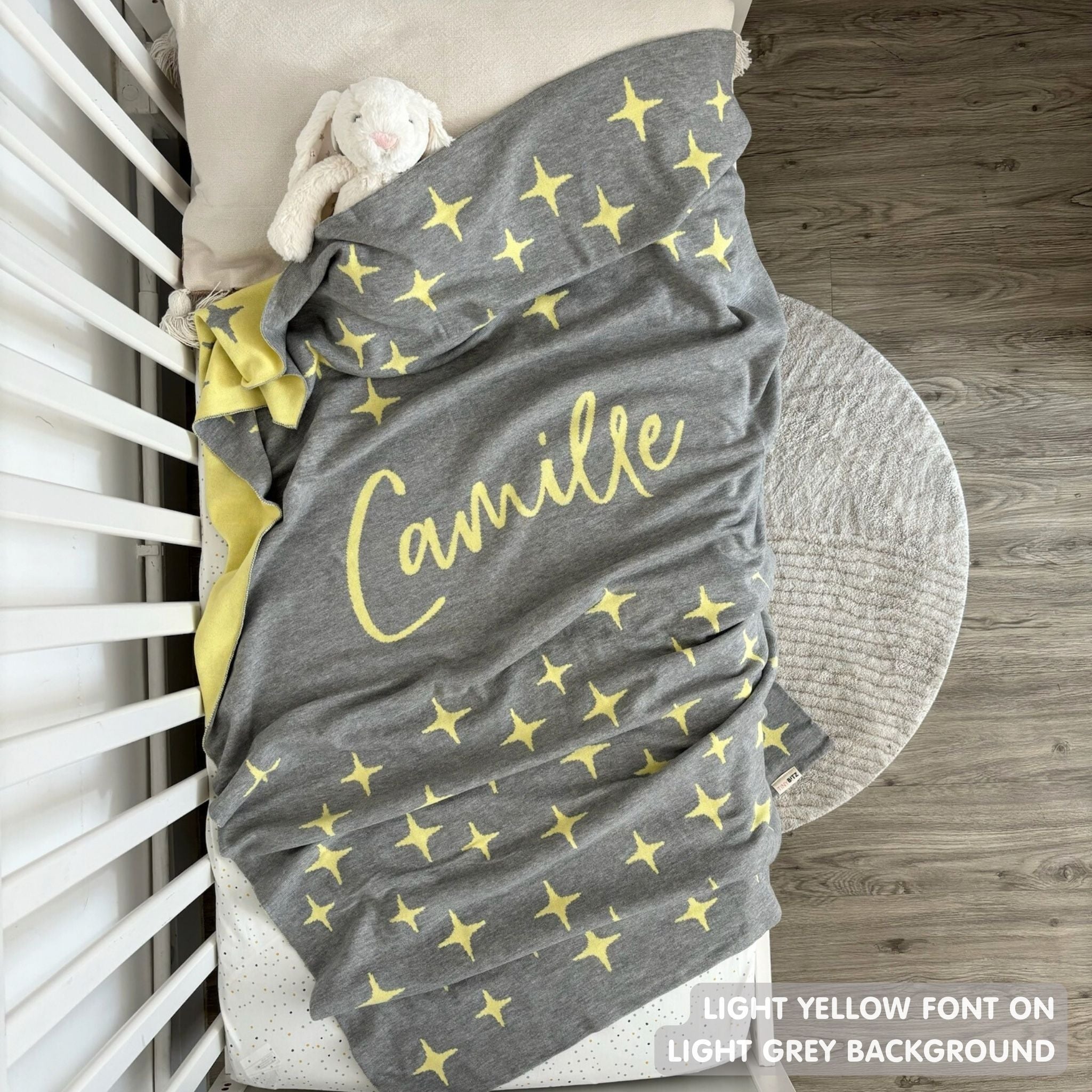 Cotton baby blanket with baby's name knitted in light grey and light yellow with a twinkles pattern, made by TinyBitz.