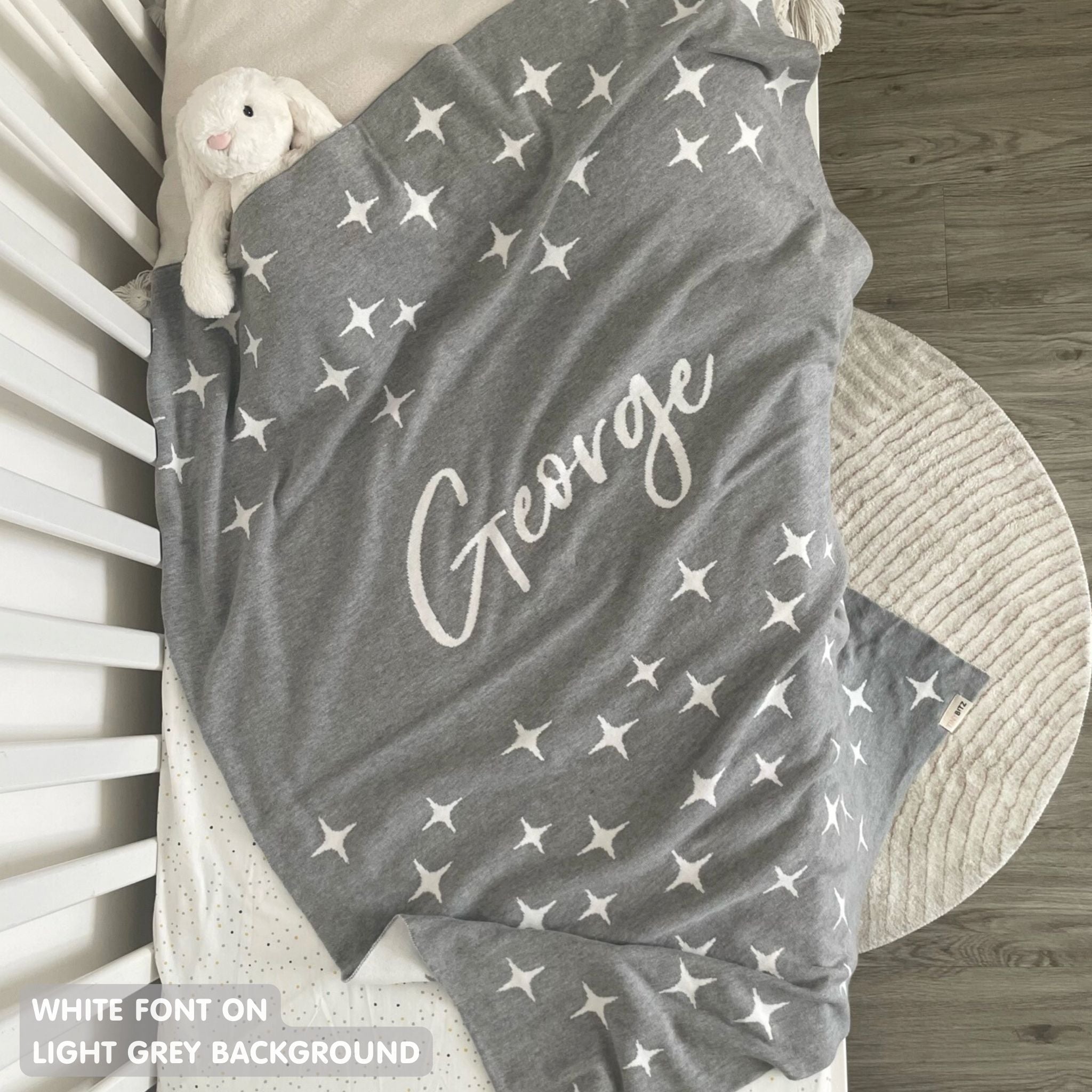 Knitted baby blanket in light grey and white with a twinkles pattern, customised with baby's name, made by TinyBitz.