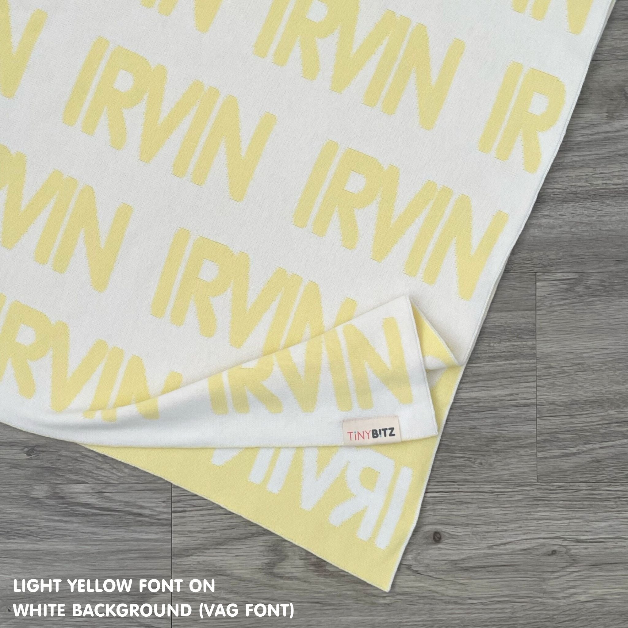 Customisable blanket with adult's name knitted in white and light yellow, personalized by TinyBitz.