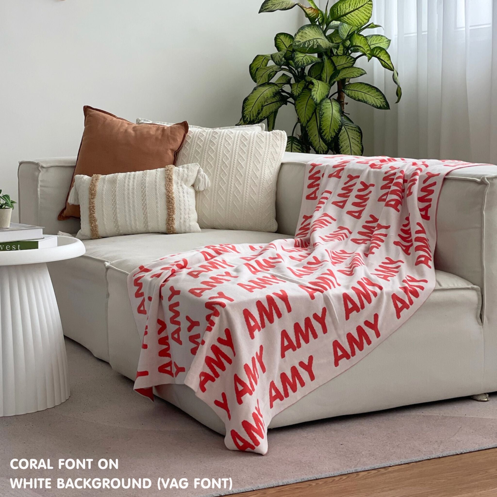 Custom name blanket draped on sofa, knitted in white and coral makes the best personalised home decor.