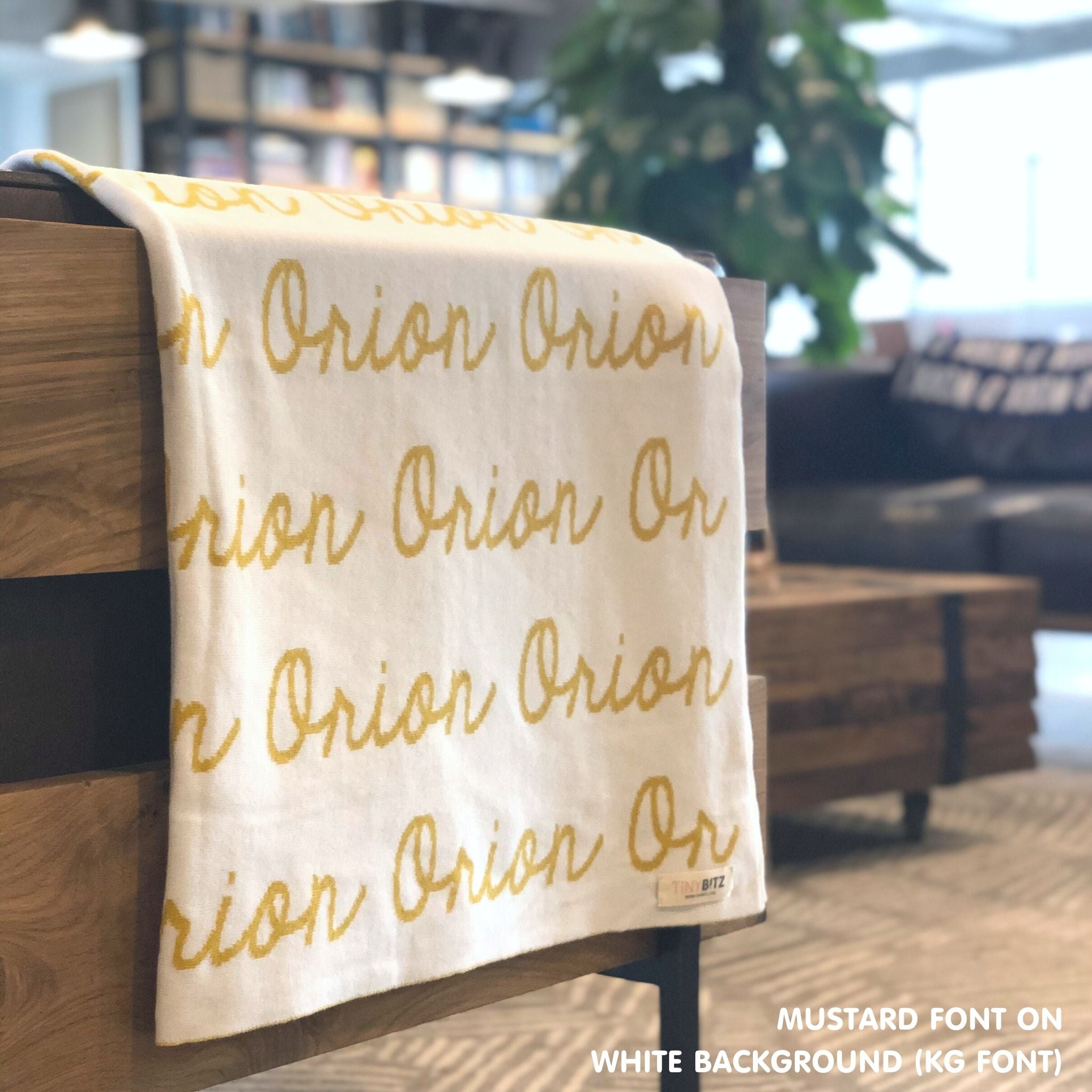 Custom name blanket in white and mustard draped over a chair makes the best personalized home decor.