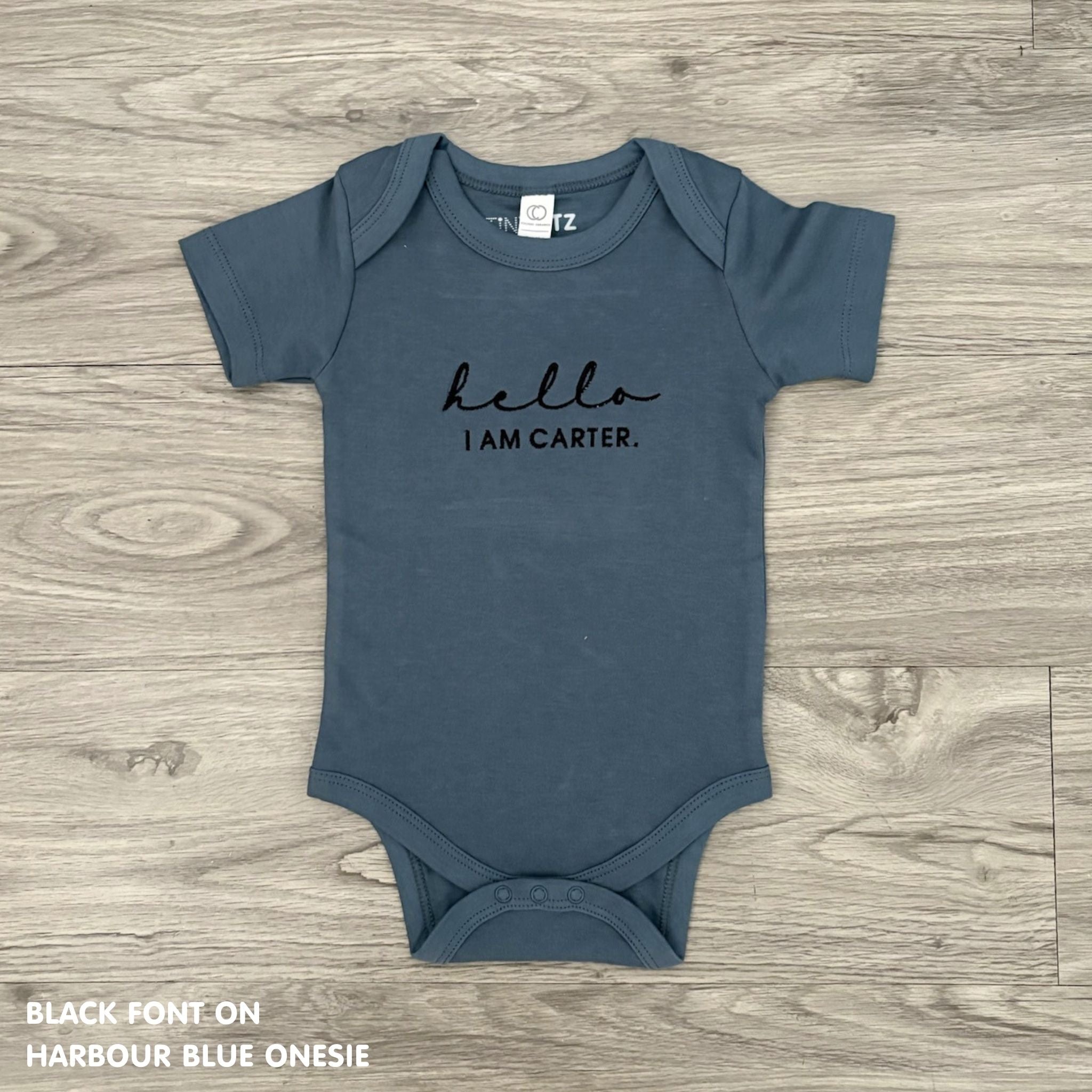 Organic cotton baby onesie with custom name, ideal for birth announcements, baby shower gifts, and keepsakes by TinyBitz.