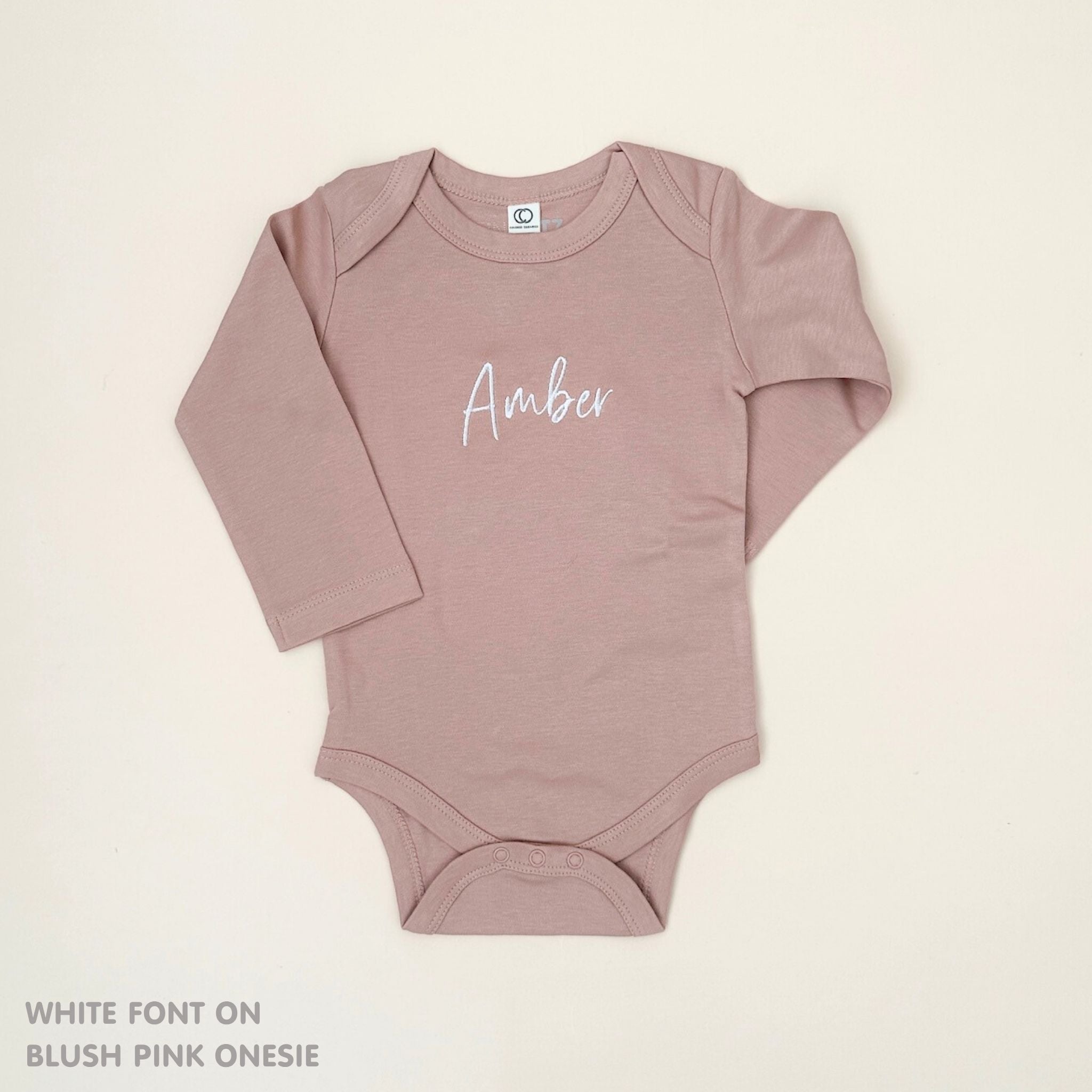 TinyBitz Personalised baby onesie with embroidered name in soft blush pink cotton, perfect for birth announcements and newborn photos.