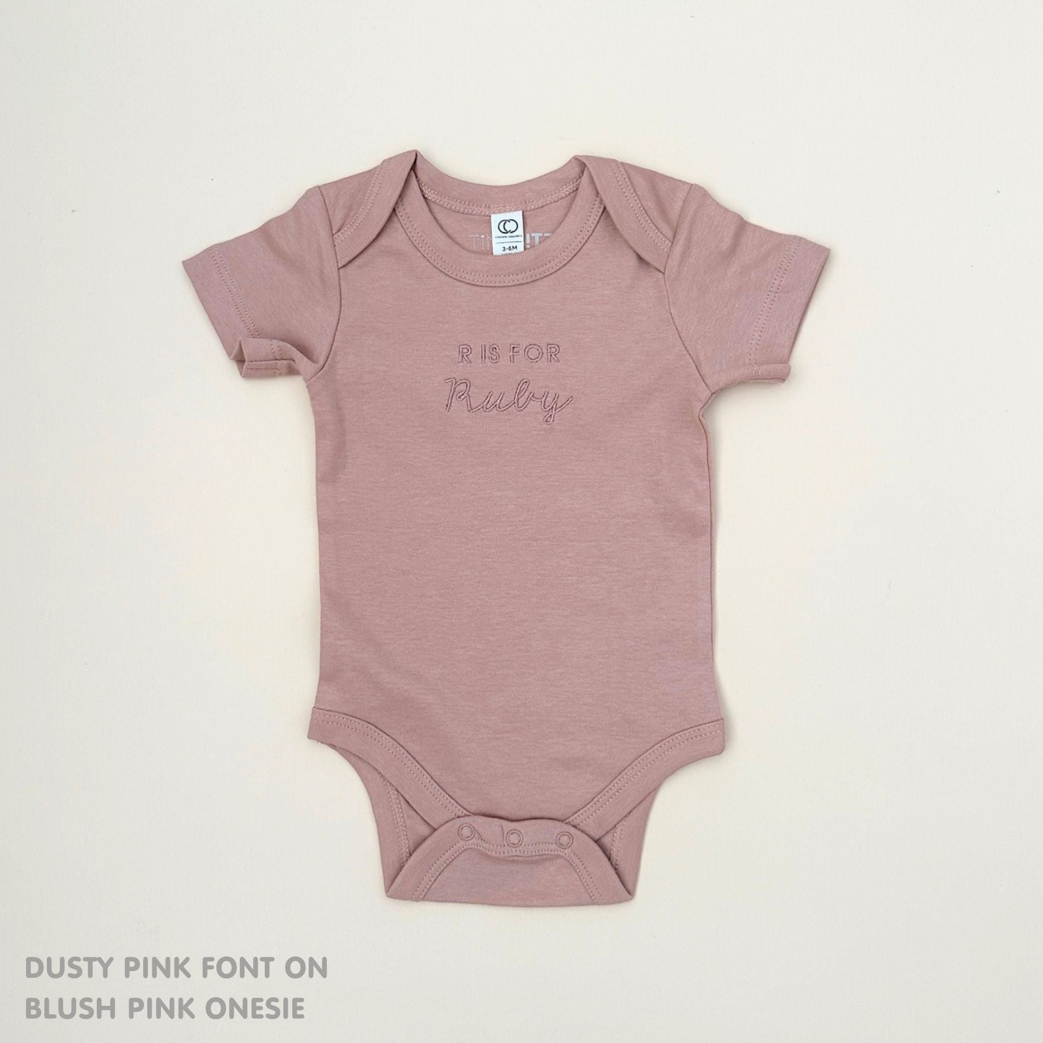 TinyBitz Personalised baby onesie with embroidered name in soft blush pink cotton, perfect for birth announcements and newborn photos.