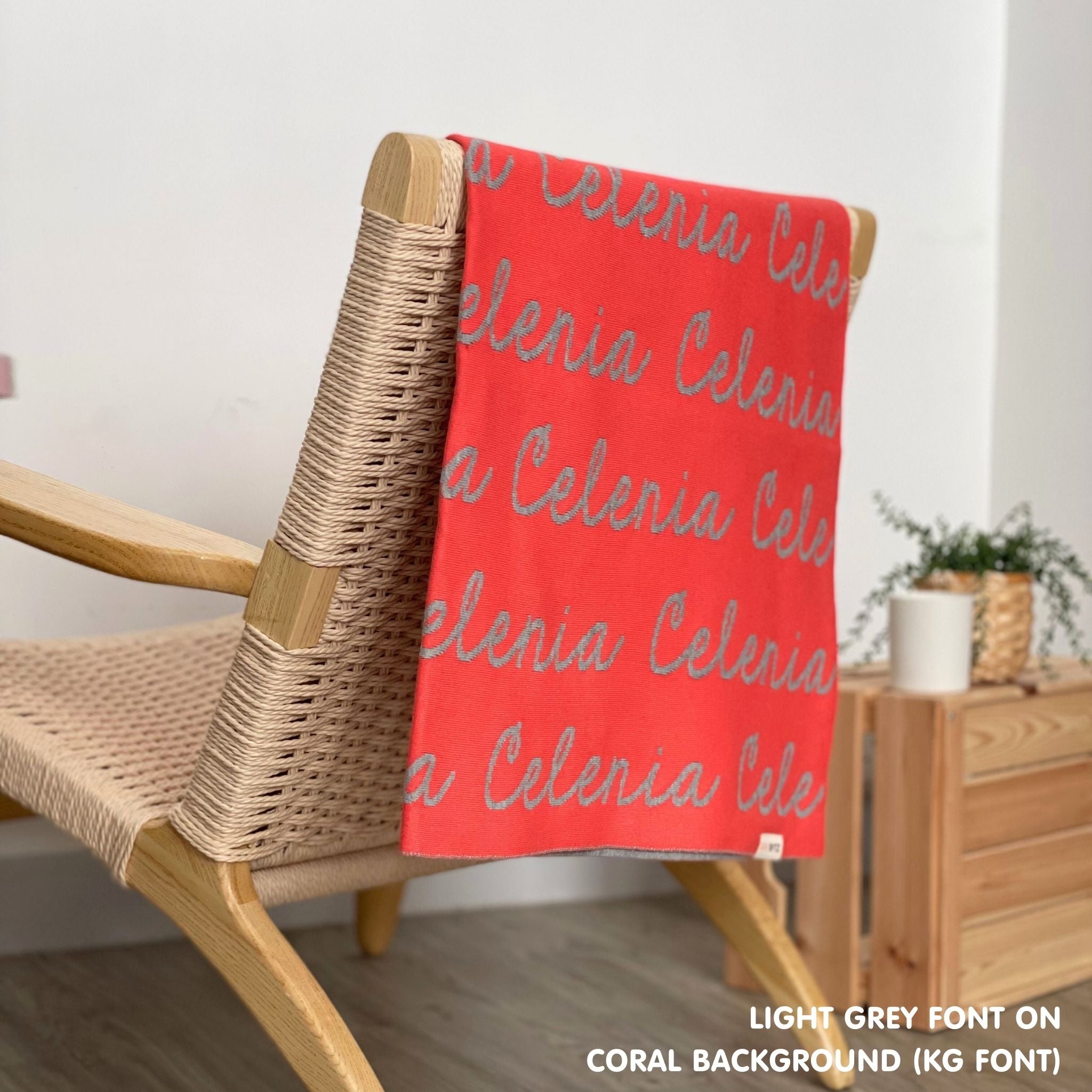 Personalised pet blanket in coral and light grey knitted cotton, custom dog blanket by TinyBitz, styled on modern wooden dog bed.