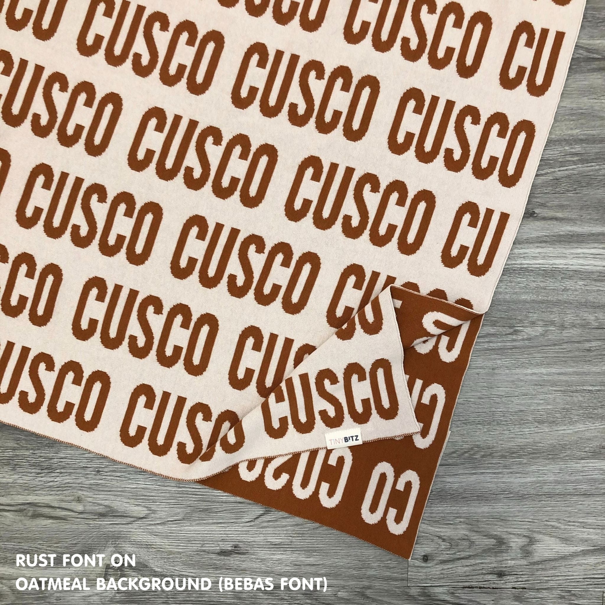 Personalised pet blanket in oatmeal and rust knitted cotton, custom dog blanket by TinyBitz, styled on modern wooden dog bed.