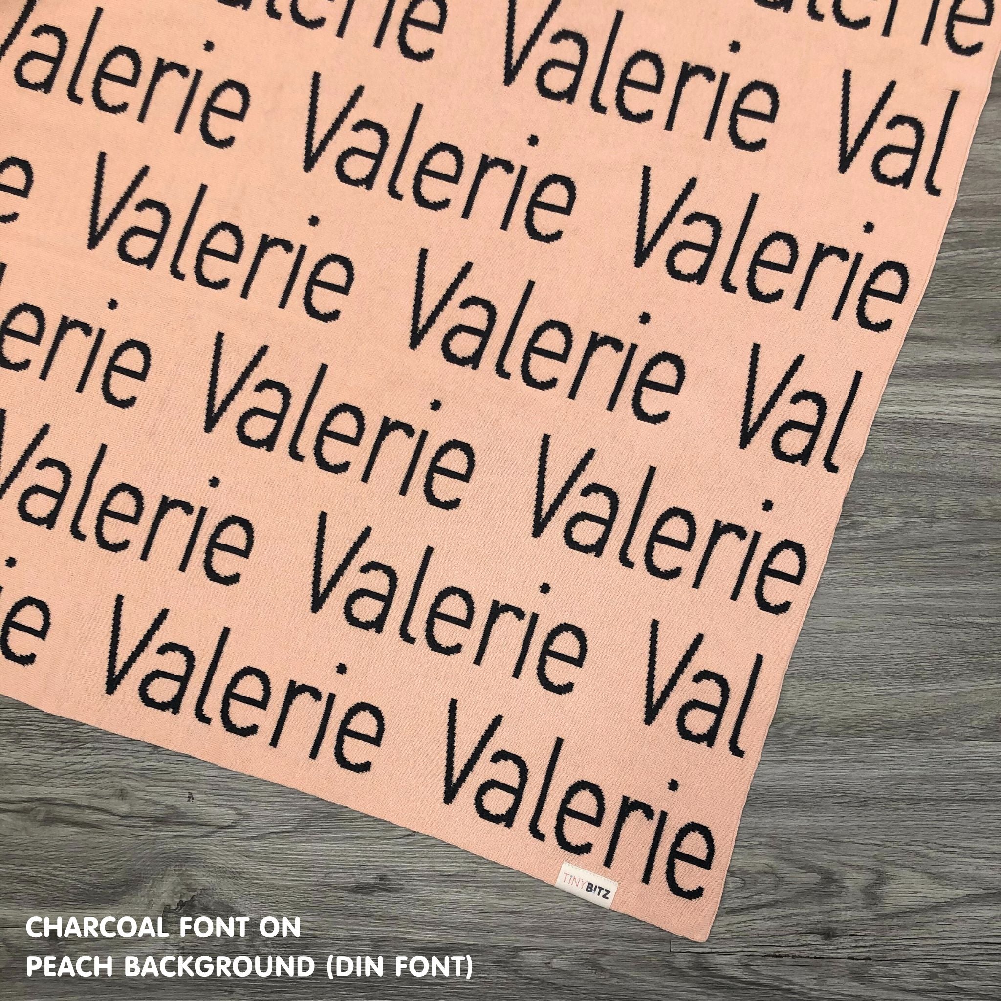 Personalised pet blanket in peach and charcoal knitted cotton, custom dog blanket by TinyBitz, styled on modern wooden dog bed.