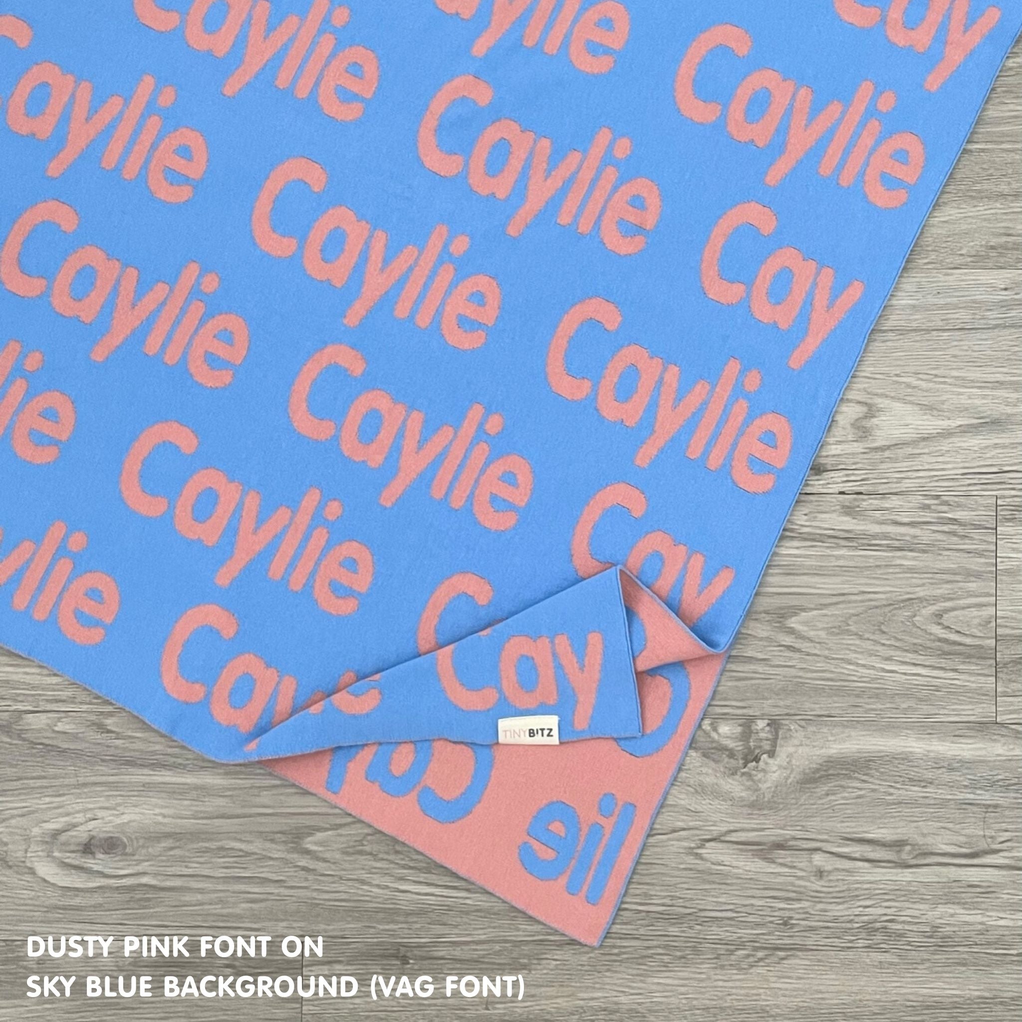 Personalised pet blanket for in sky blue and dusty pink knitted cotton, custom dog blanket by TinyBitz, styled on modern wooden dog bed.