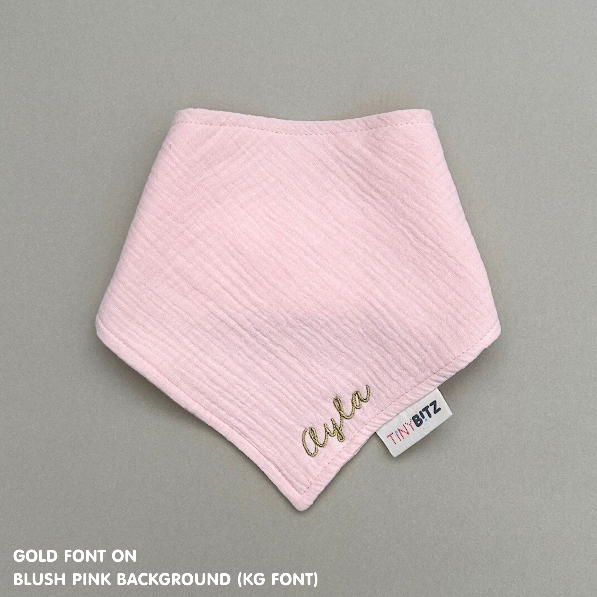 Personalized blush pink organic muslin bib with custom name embroidery, perfect for baby gifts and keepsake accessories.