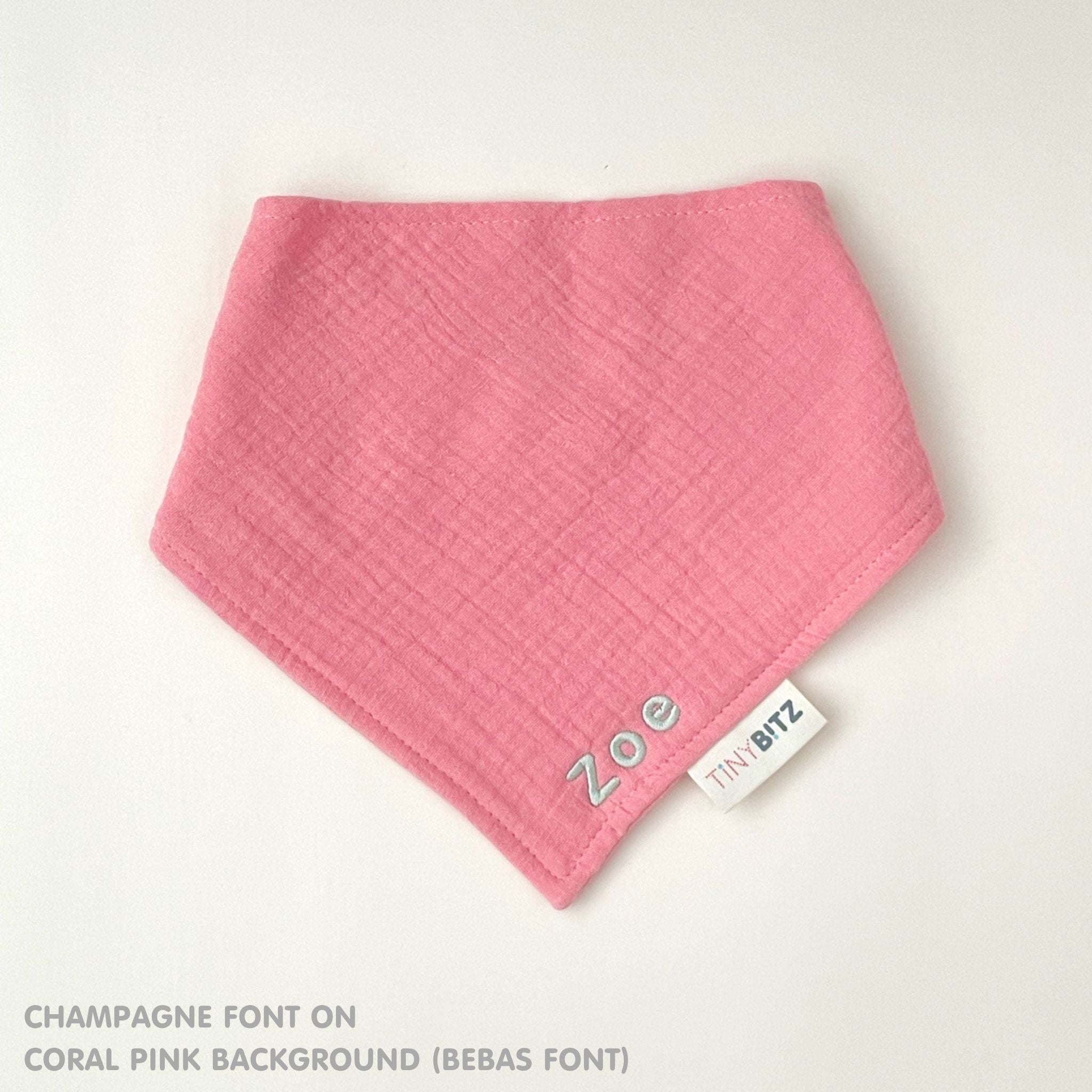Organic personalised bib for babies in coral pink, featuring baby name in script font, unique baby gift idea by TinyBitz.